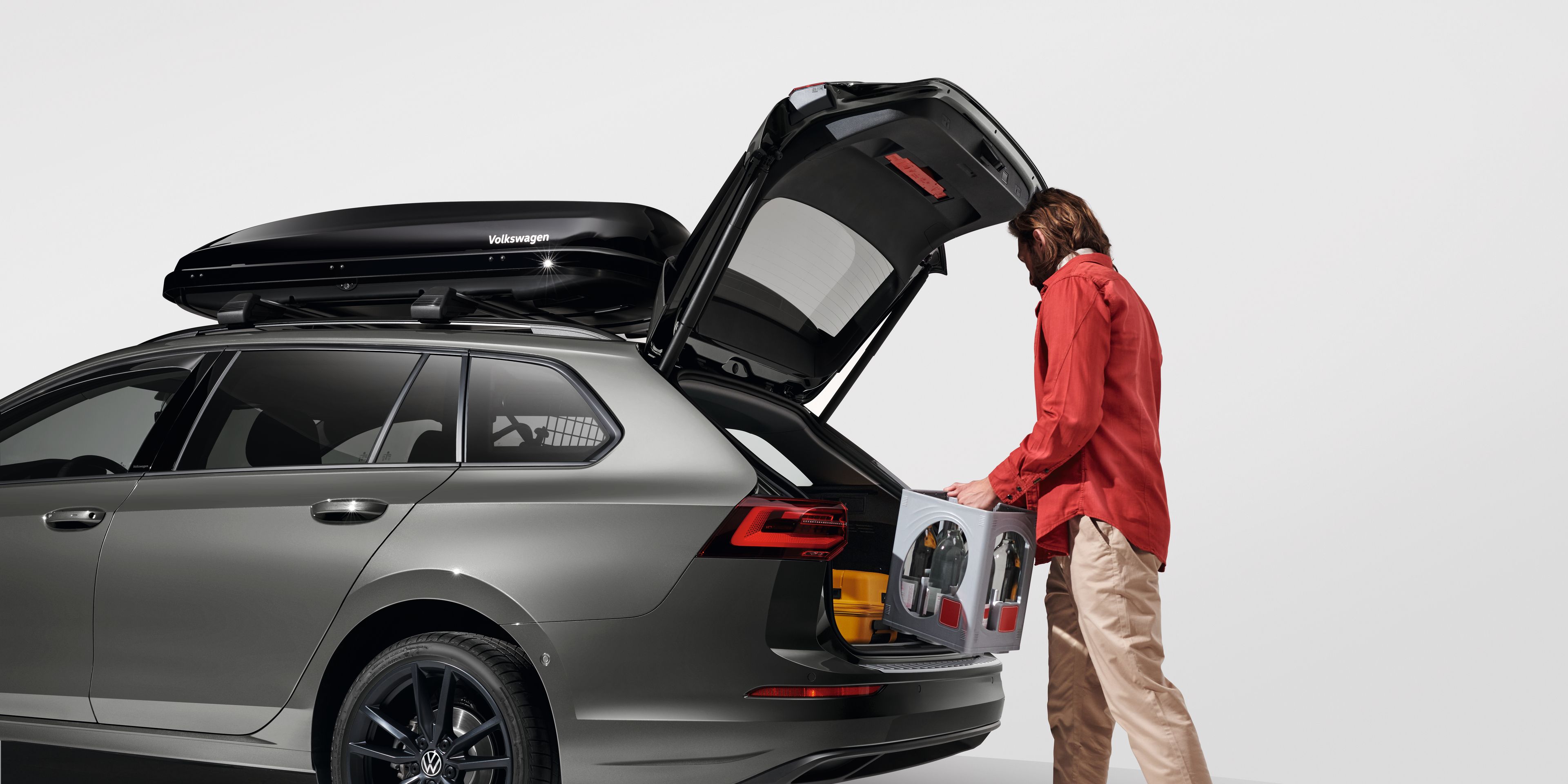 Ein Mann belädt den Kofferraum eines Volkswagen Golf Variant
