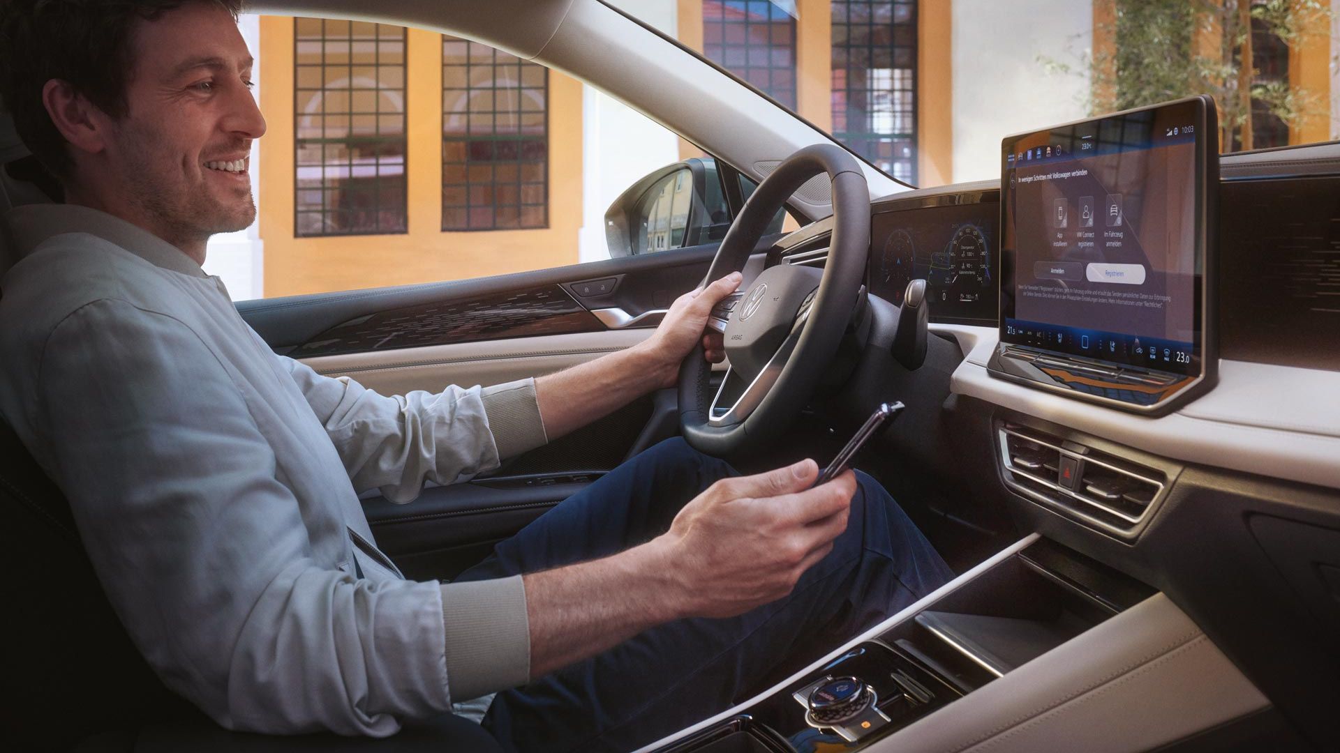Mann sitzt in VW Tiguan und hält Smartphone in der Hand