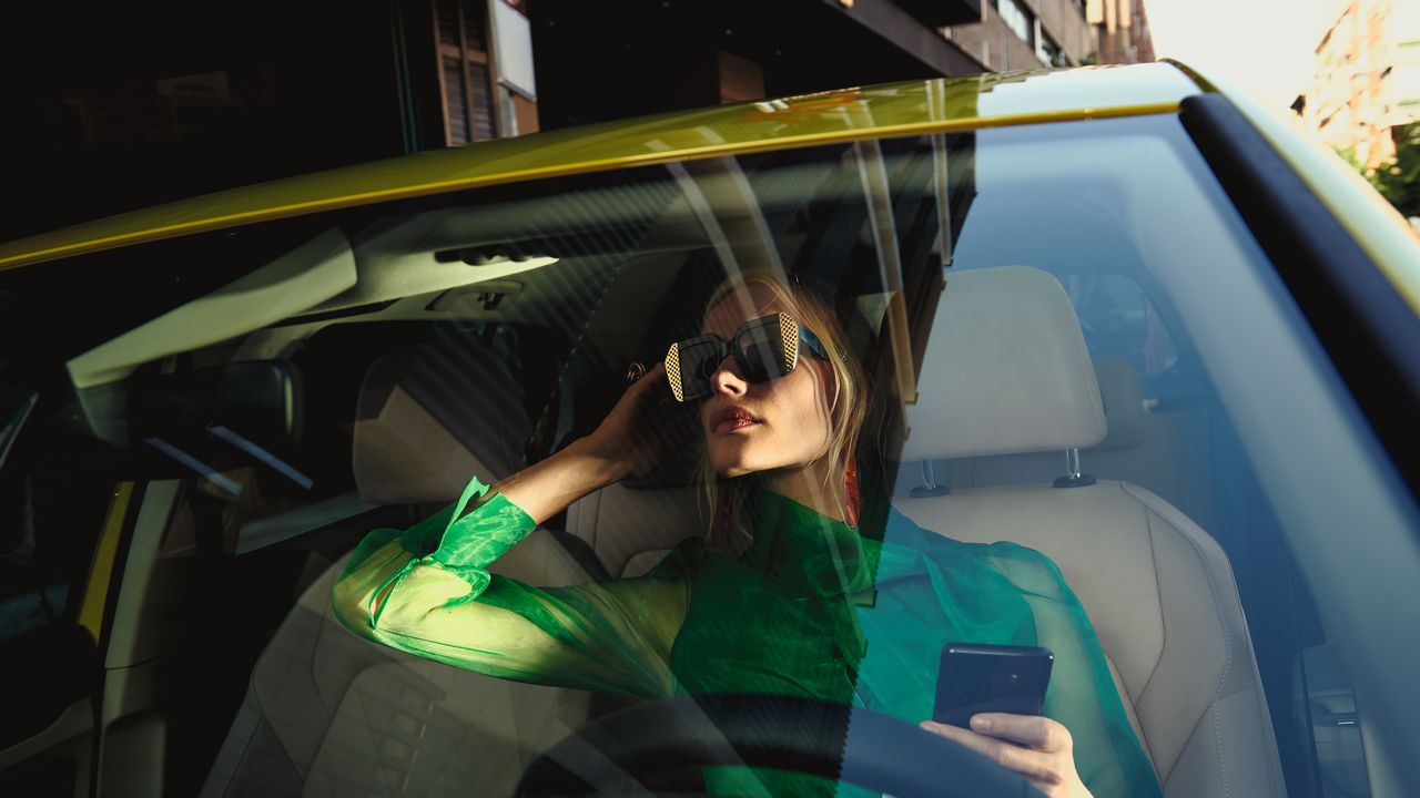 Eine Frau sitzt auf dem Fahrersitz im VW Golf und prüft ihr Aussehen im Rückspiegel.
