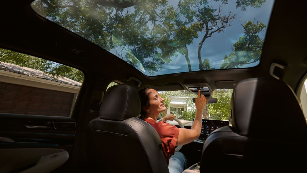 Frau sitzt in VW ID.7 und bedient per Knopfdruck das Sonnenrollo des Panoramadachs