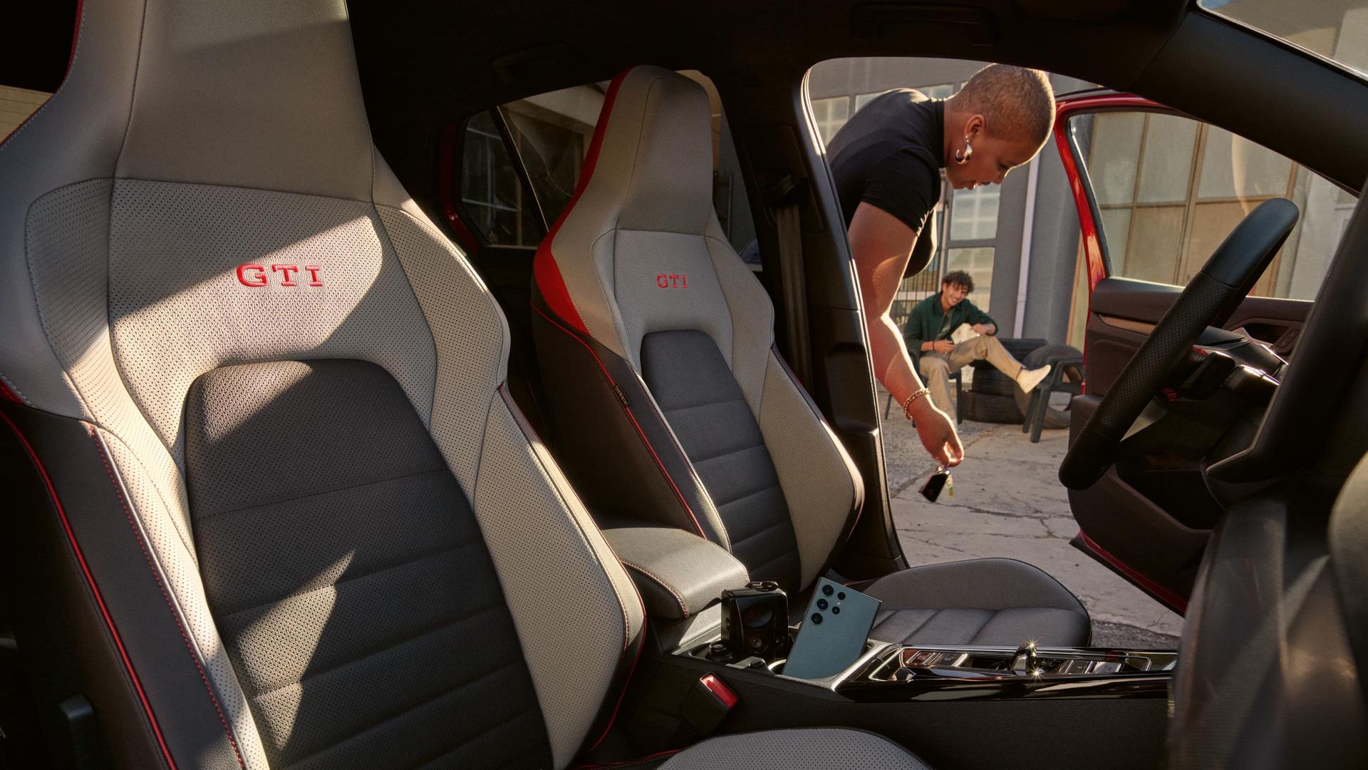Ansicht der Frontsitze eines VW Golf GTI, Frau öffnet die Fahrertür