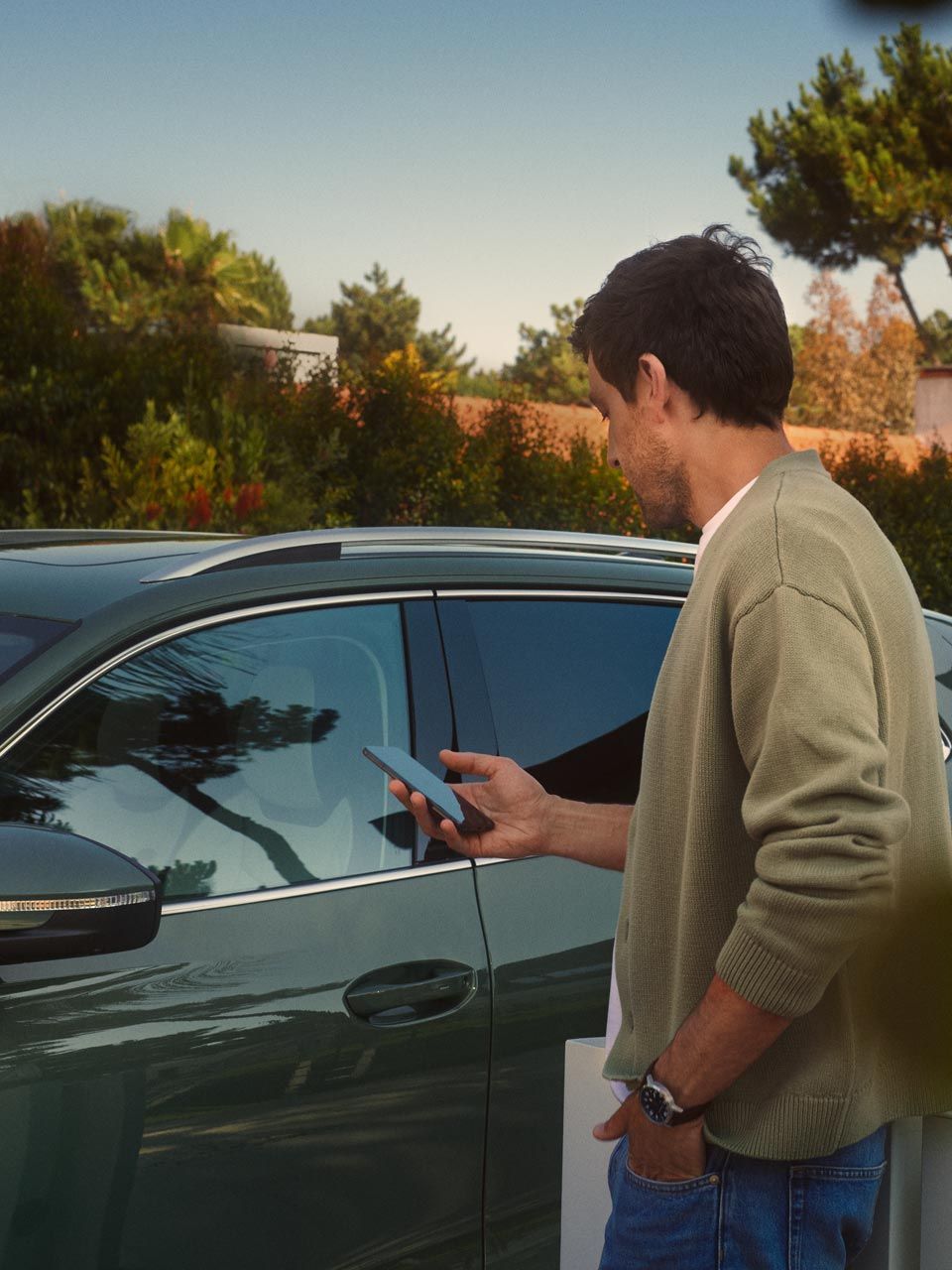 Mann bedient Park Assist des VW Tiguan auf seinem Smartphone