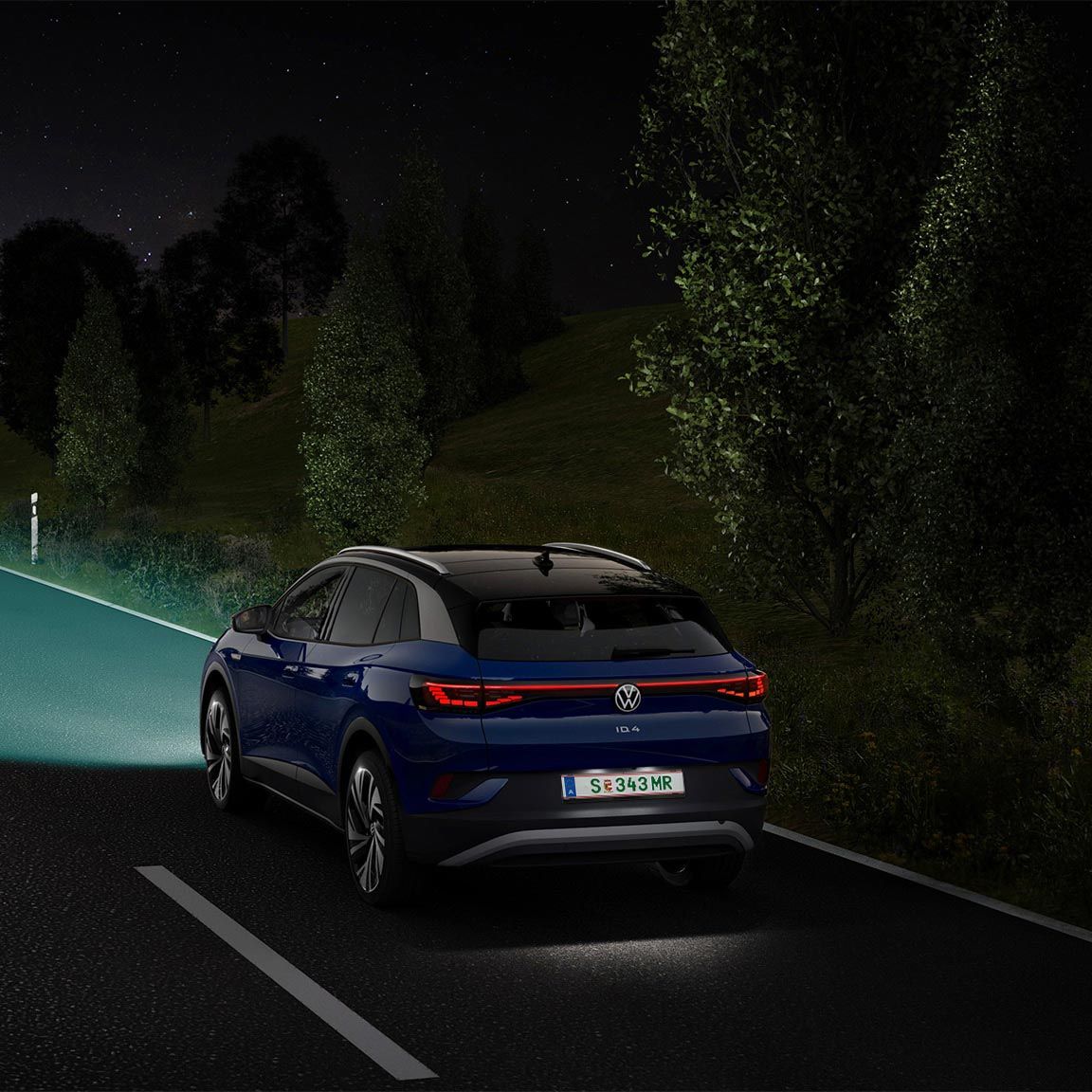 Ein blauer VW ID.4 fährt mit eingeschaltetem Licht eine nächtliche Straße entlang.