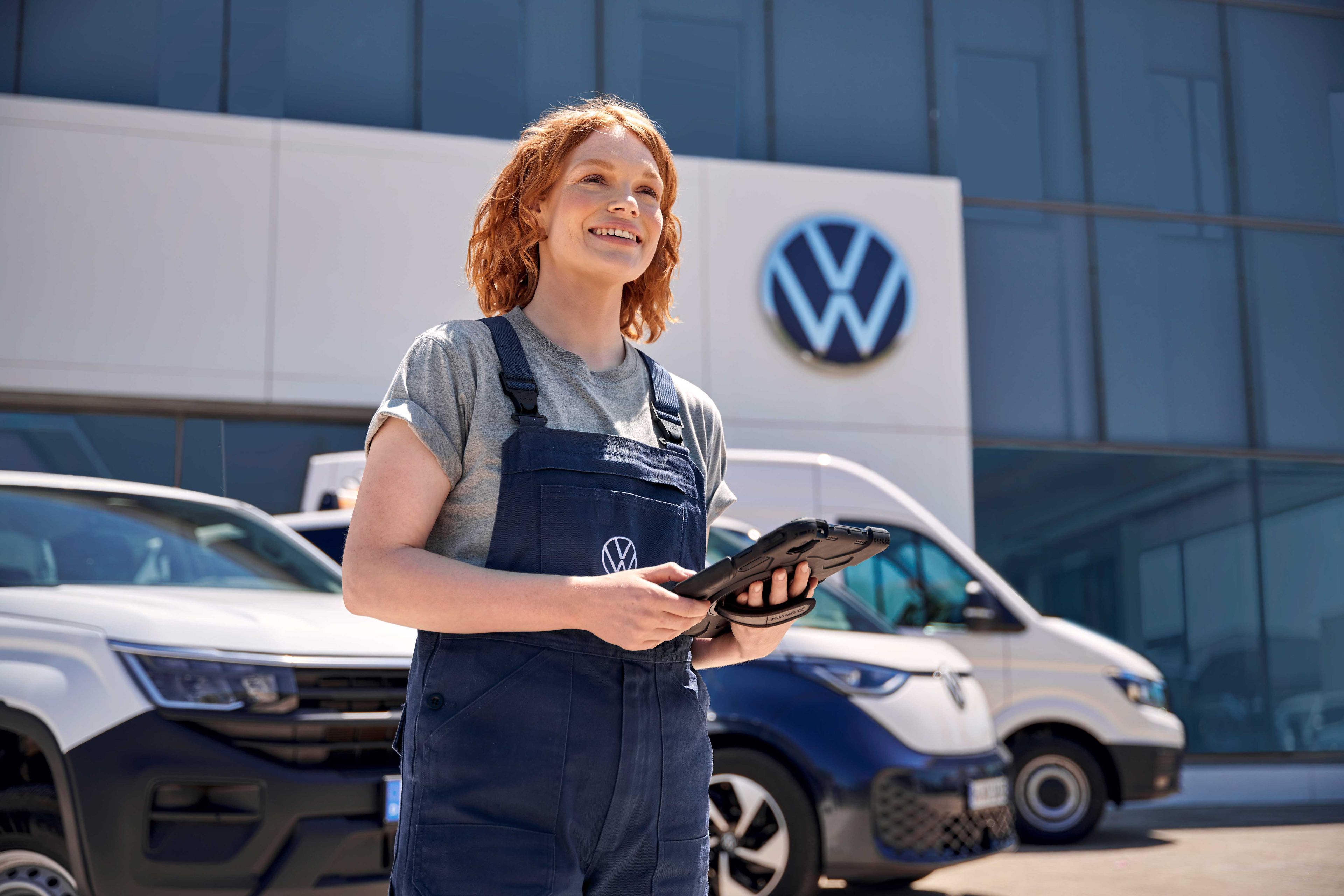 Eine Volkswagen Service Mitarbeiterin vor einem Volkswagen Service Gebäude