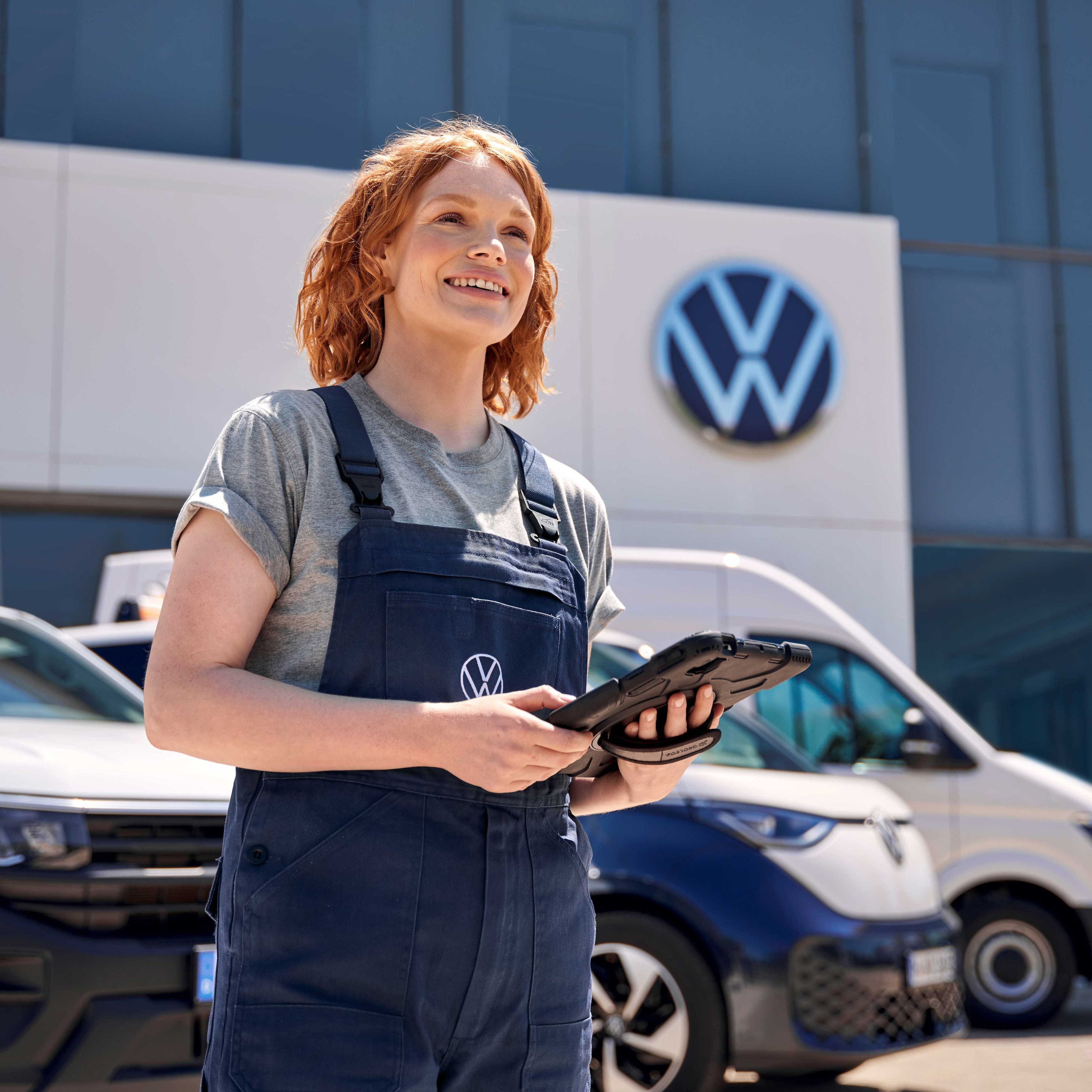 Eine Volkswagen Service Mitarbeiterin vor einem Volkswagen Service Gebäude