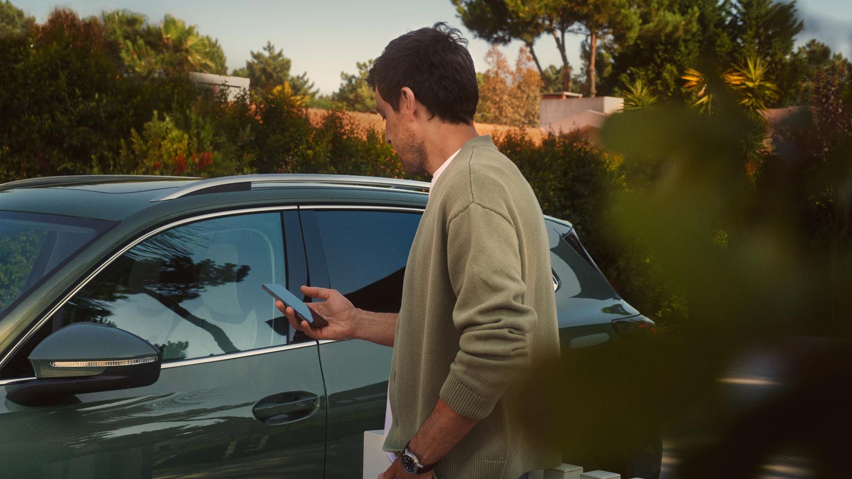 Mann bedient Park Assist des VW Tiguan auf seinem Smartphone