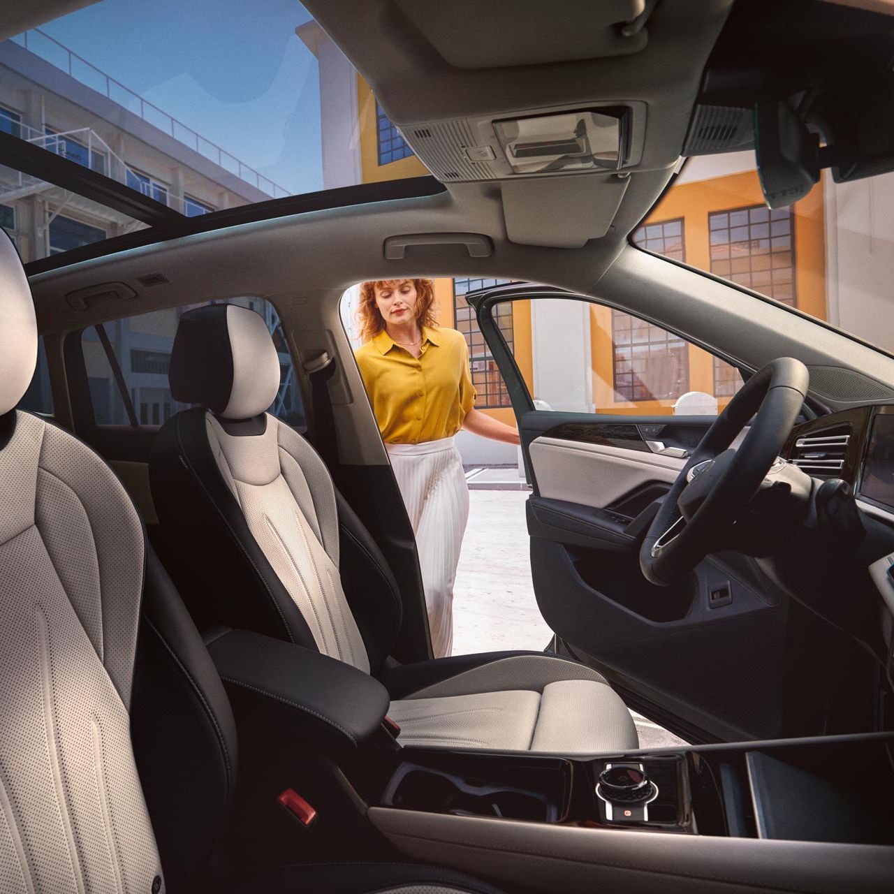 Innenansicht eines VW Tiguan mit Panoramadach und weißen Sitzen, Frau öffnet Fahrertür