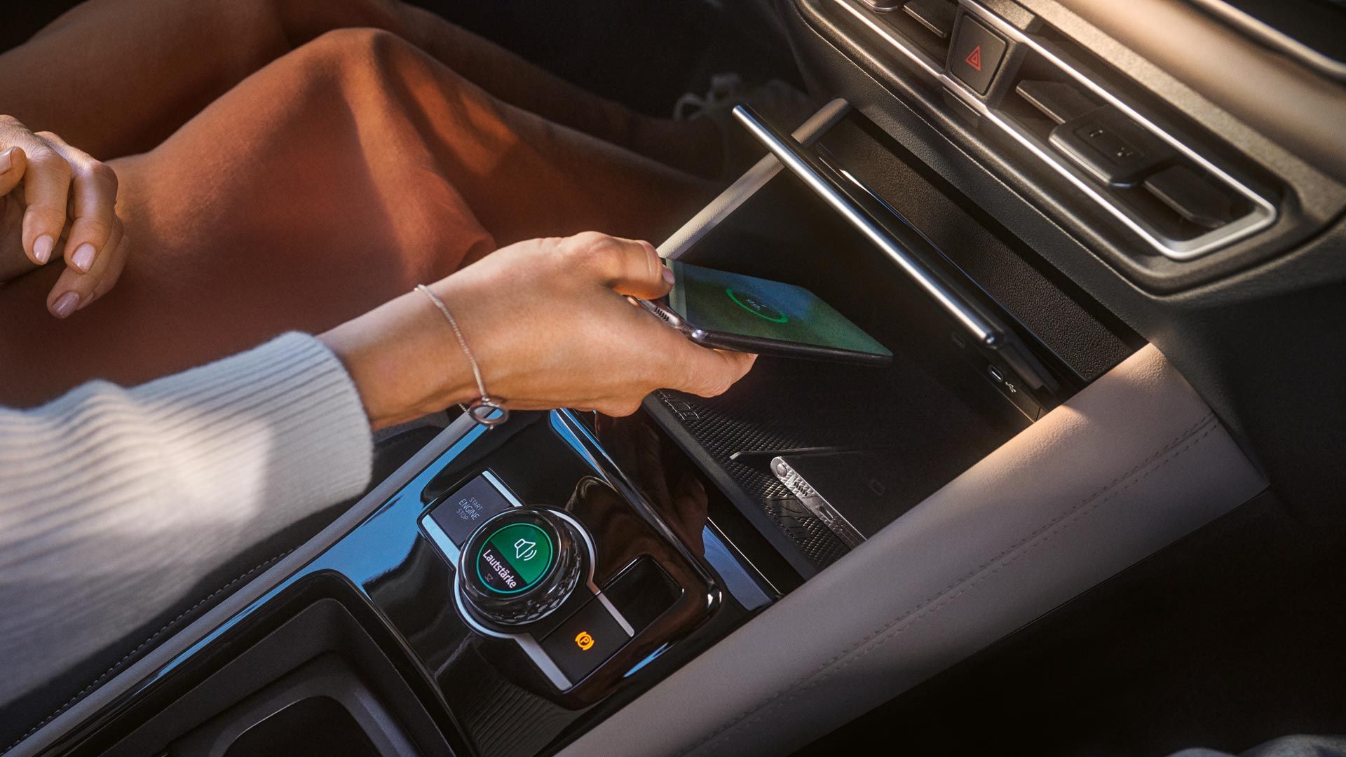 Person legt Smartphone in Ablage für Wireless Charging im VW Tiguan