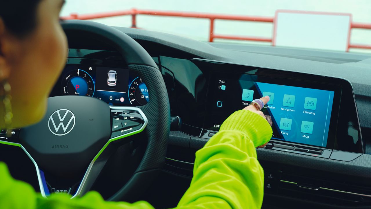 VW Golf GTE Interieur, Frau bedient den Home-Screen des optionalen Navigationssystems „Discover Pro“ als Teil des Innovision Cockpits.