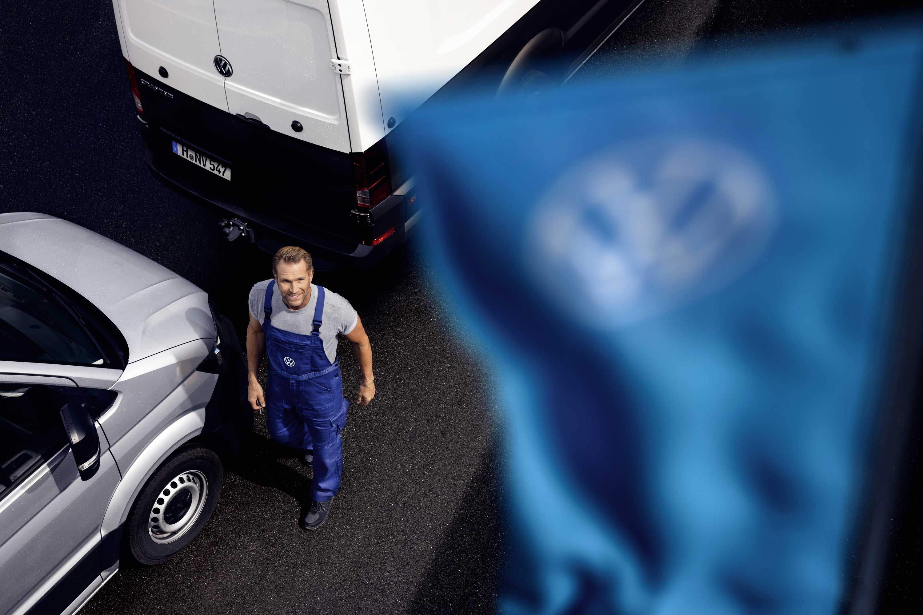 VW Service Mitarbeiter mit Volkswagen Nutzfahrzeugen zu den Volkswagen Vorteilspaketen