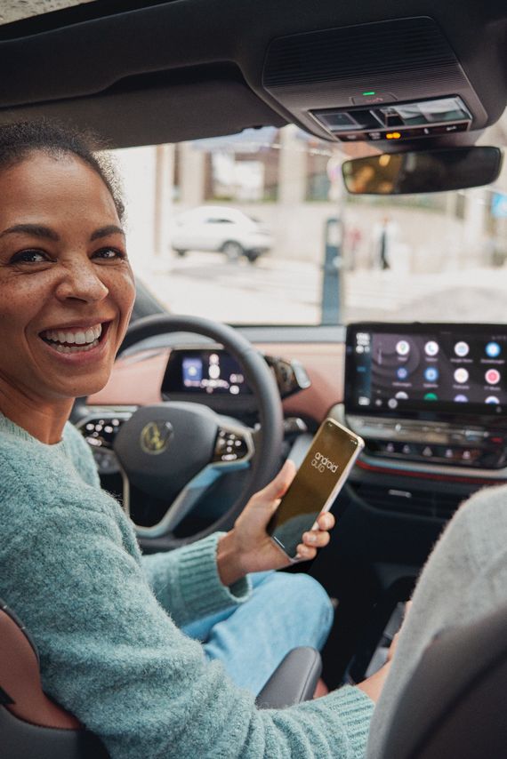 Frau bedient mit Ihrem Smartphone App Connect in Ihrem VW ID.5