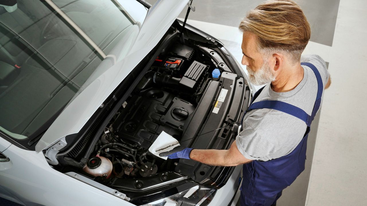 Ein VW Service Techniker misst den Ölstand bei einem Volkswagen Sharan