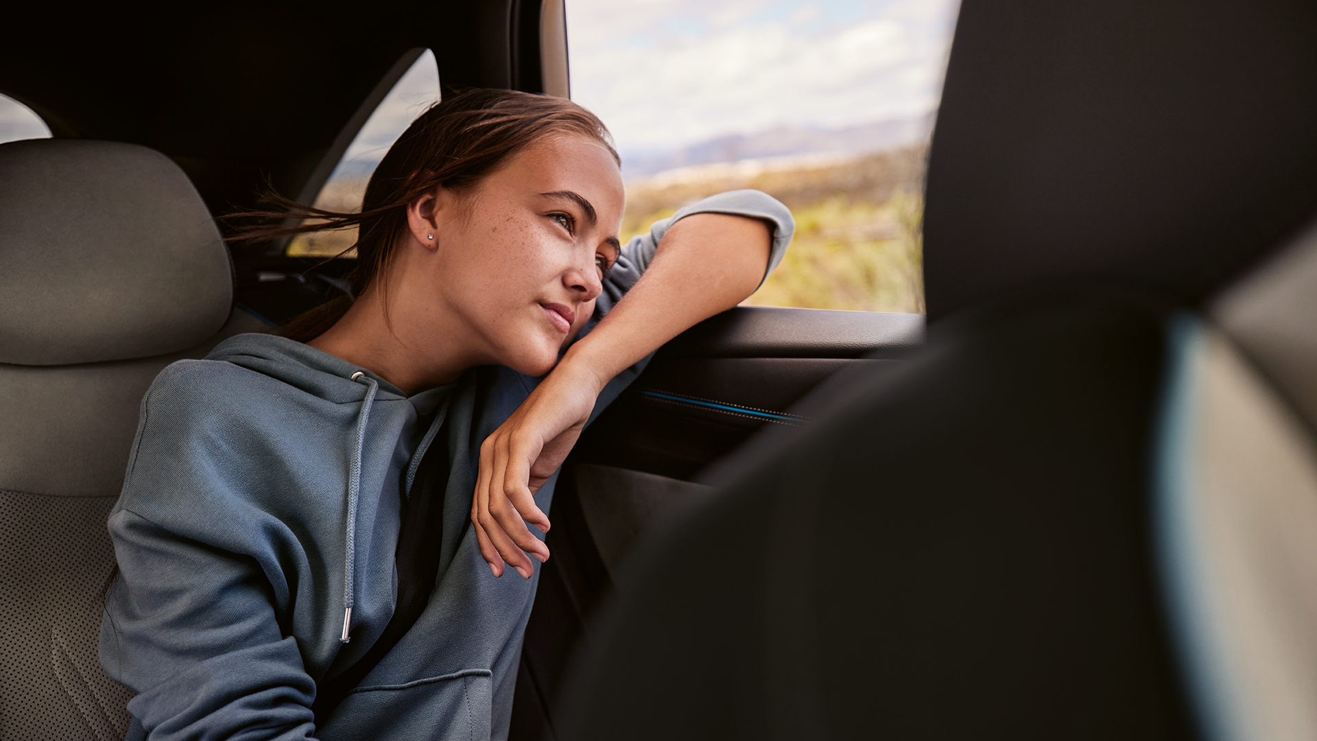 Ein Mädchen am Rücksitz eines VW ID.7 sieht während der Fahrt aus dem Fenster