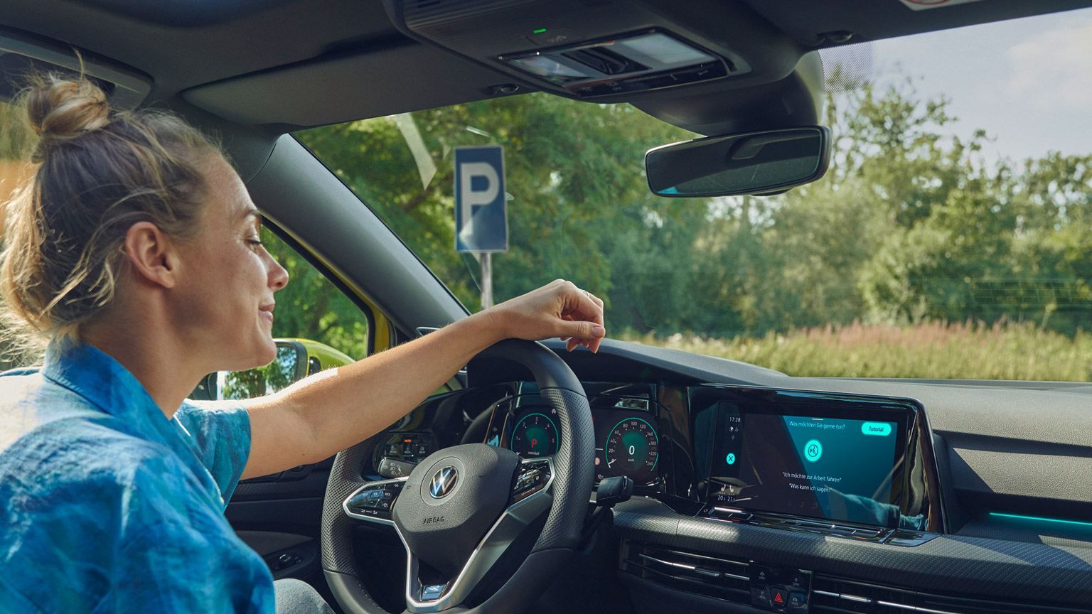 Frau sitzt im VW Golf Variant und nutzt die Sprachbedienung