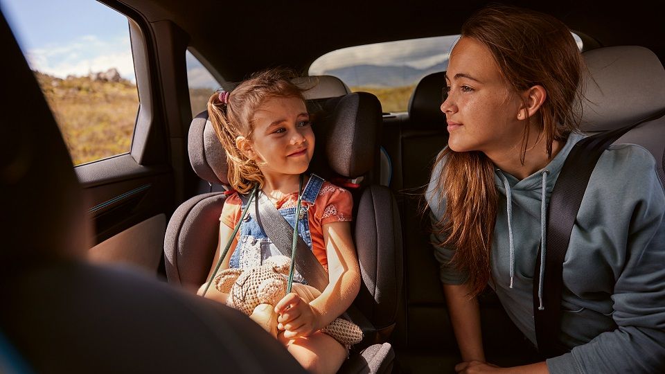Zwei Mädchen sitzen auf der Rückbank des VW ID.7 und lächeln