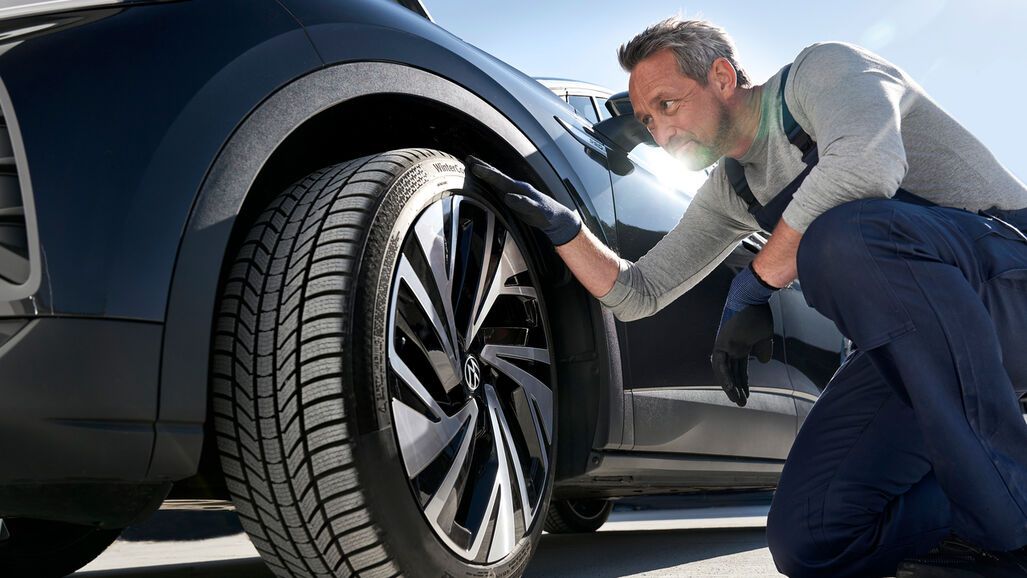 Ein Volkswagen Techniker prüft die Reifen eines Volkswagen