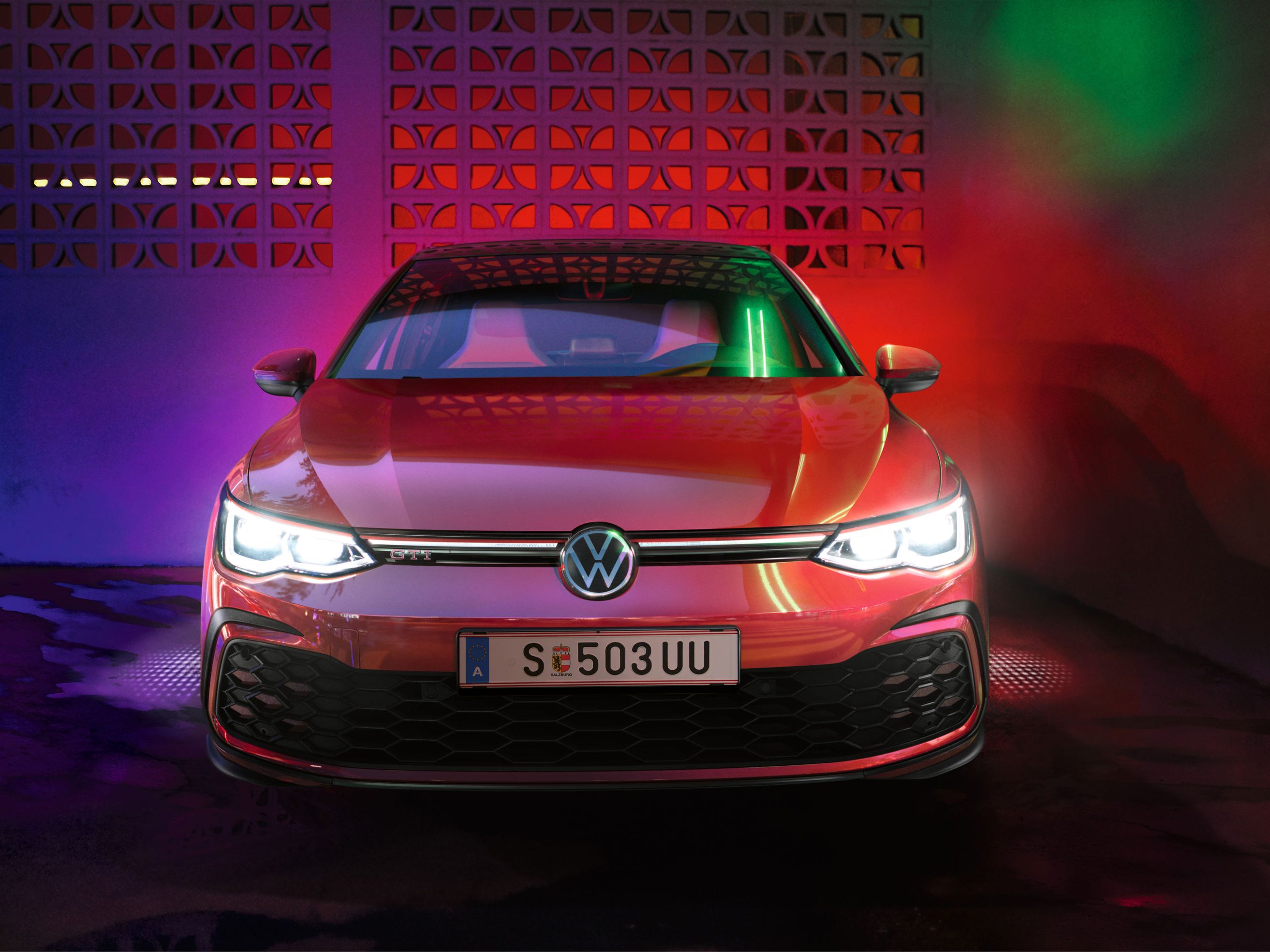 Frontansicht des VW Golf GTI mit bunten Lichtern im Hintergrund