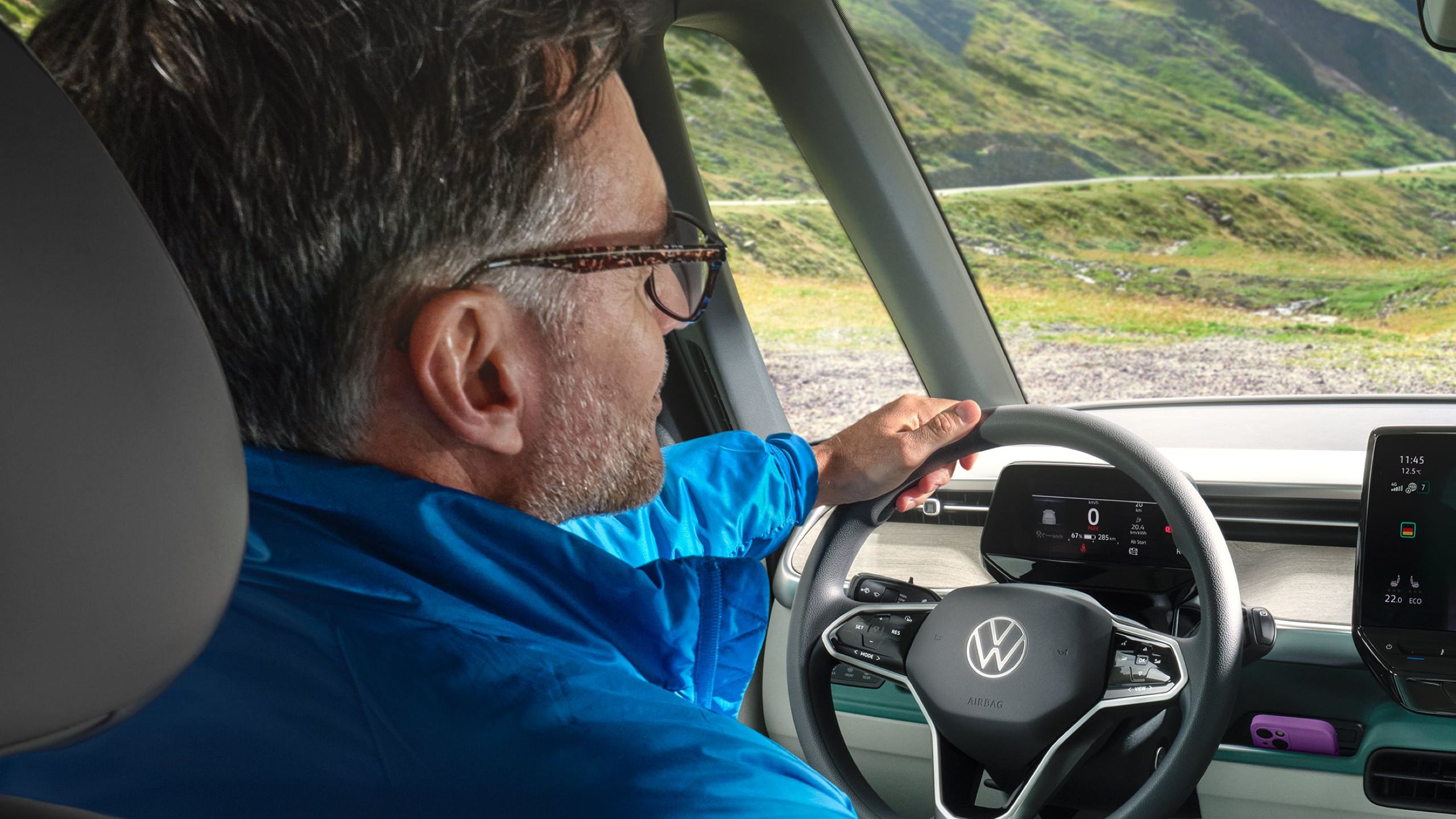 Fahrer im VW ID. Buzz mit Blick auf Berge