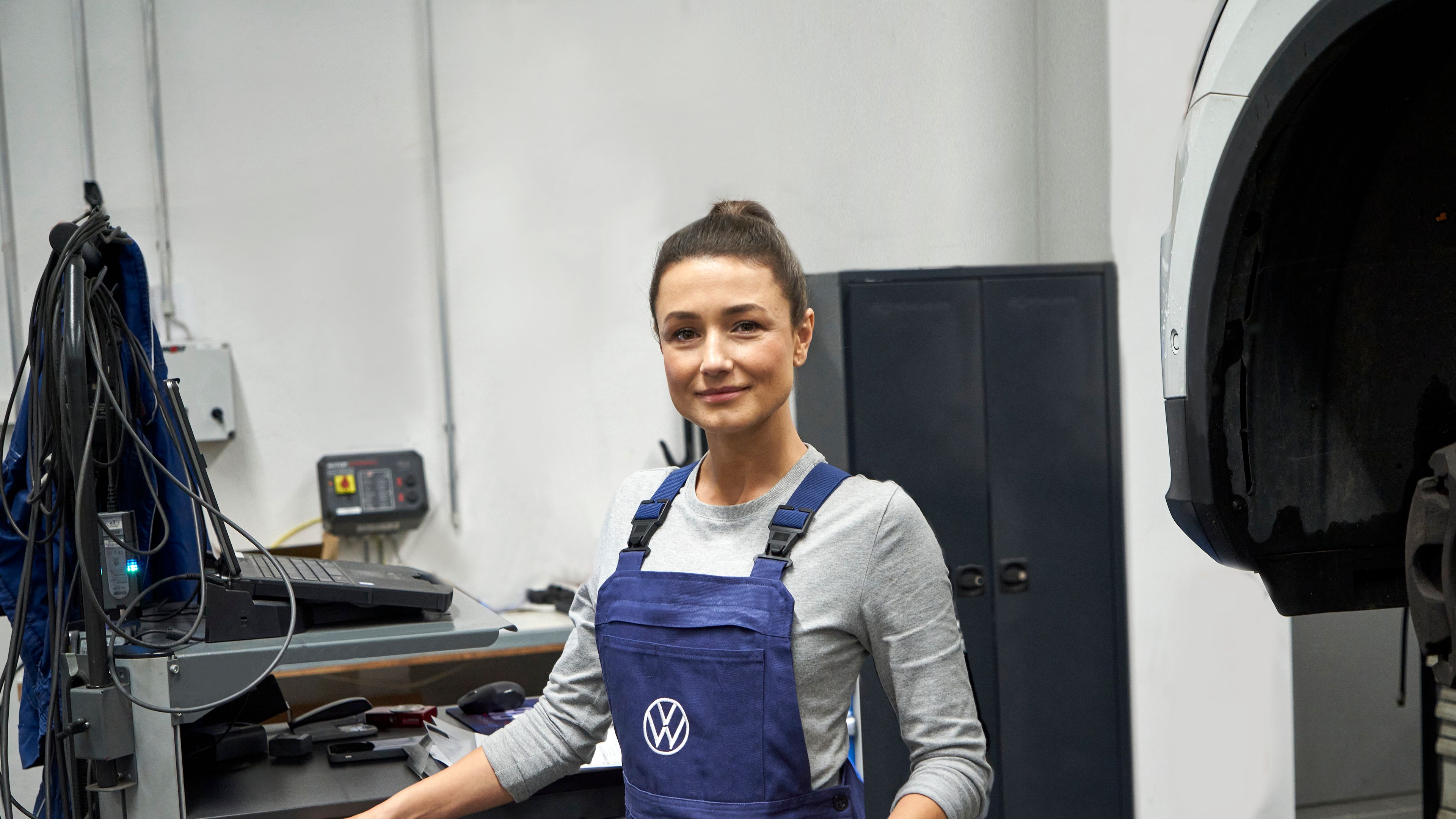 Eine Volkswagen Service Technikerin neben einem Pult mit technischer Ausrüstung