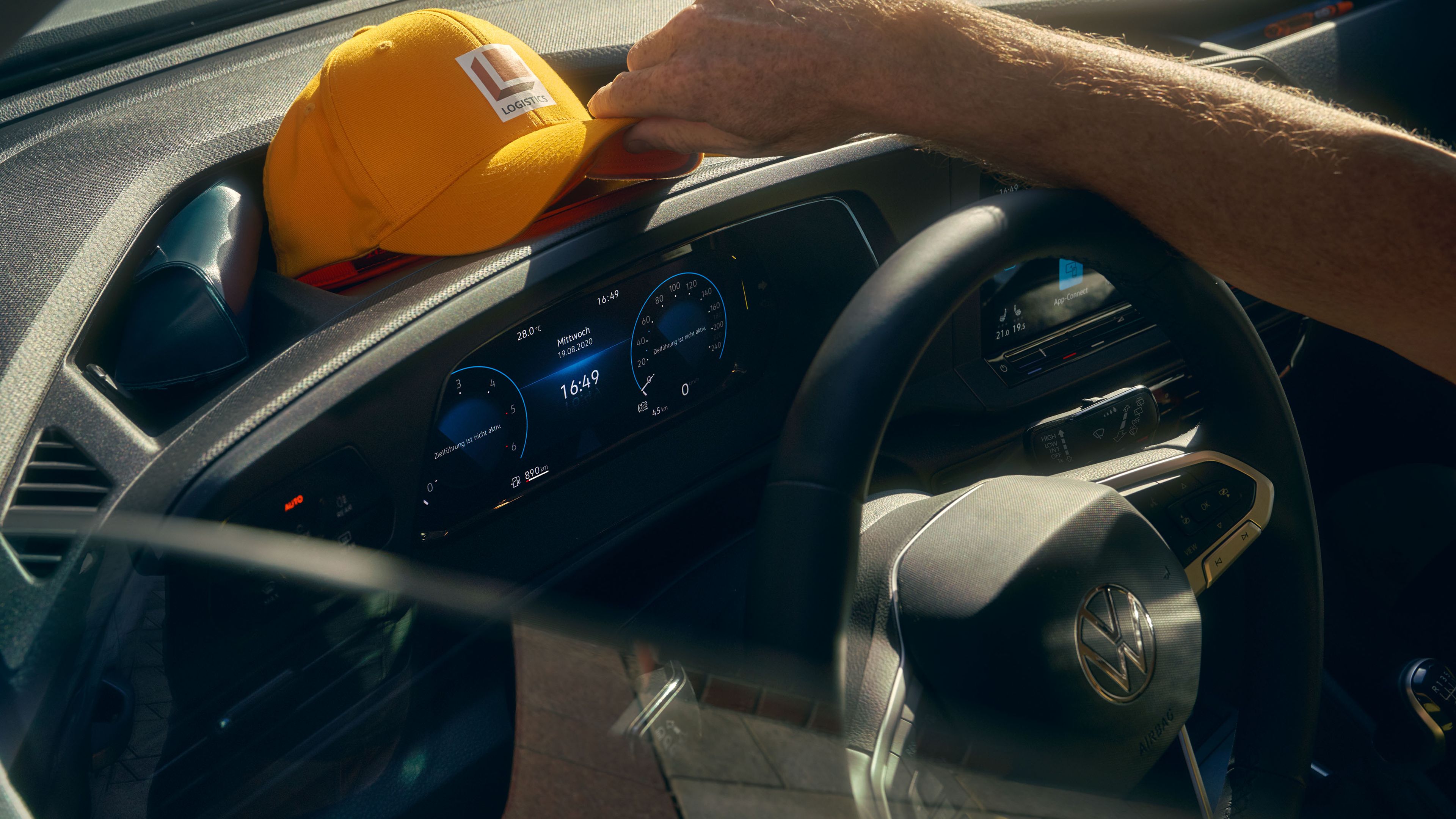 Ein Mann legt seine Kappe auf die Ablagefläche auf dem Armaturenbrett eines VW Caddy Cargo.