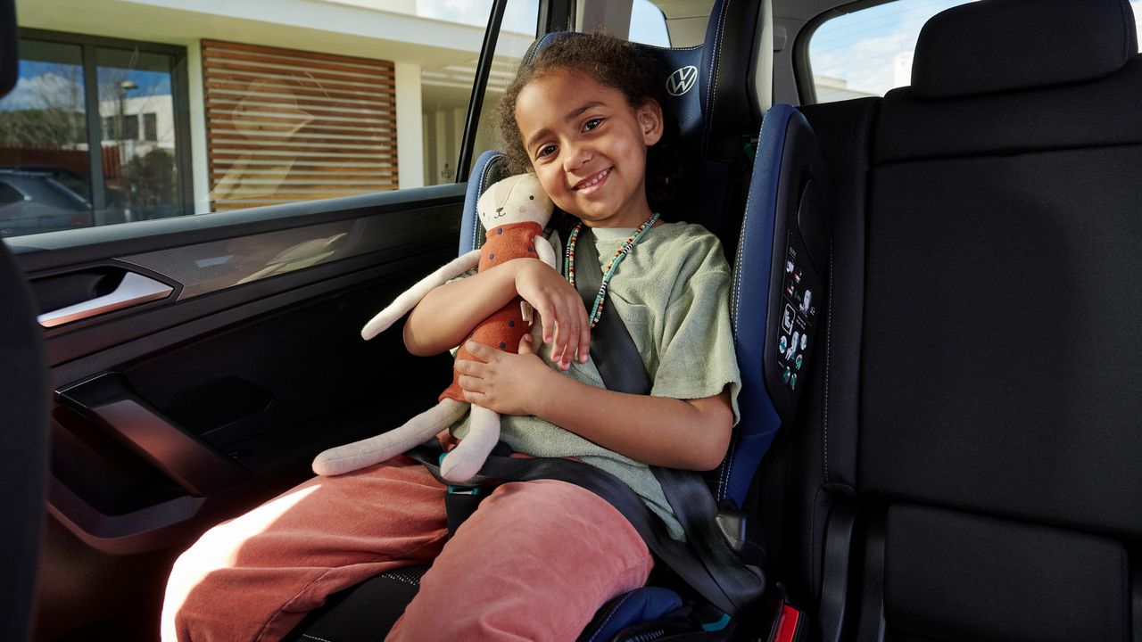 VW i-SIZE Kindersitz auf der Rückbank montiert, ein Mädchen mit Kuscheltier sitzt darin