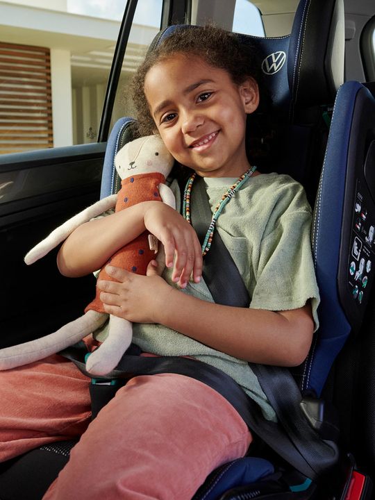 VW i-SIZE Kindersitz auf der Rückbank montiert, ein Mädchen mit Kuscheltier sitzt darin