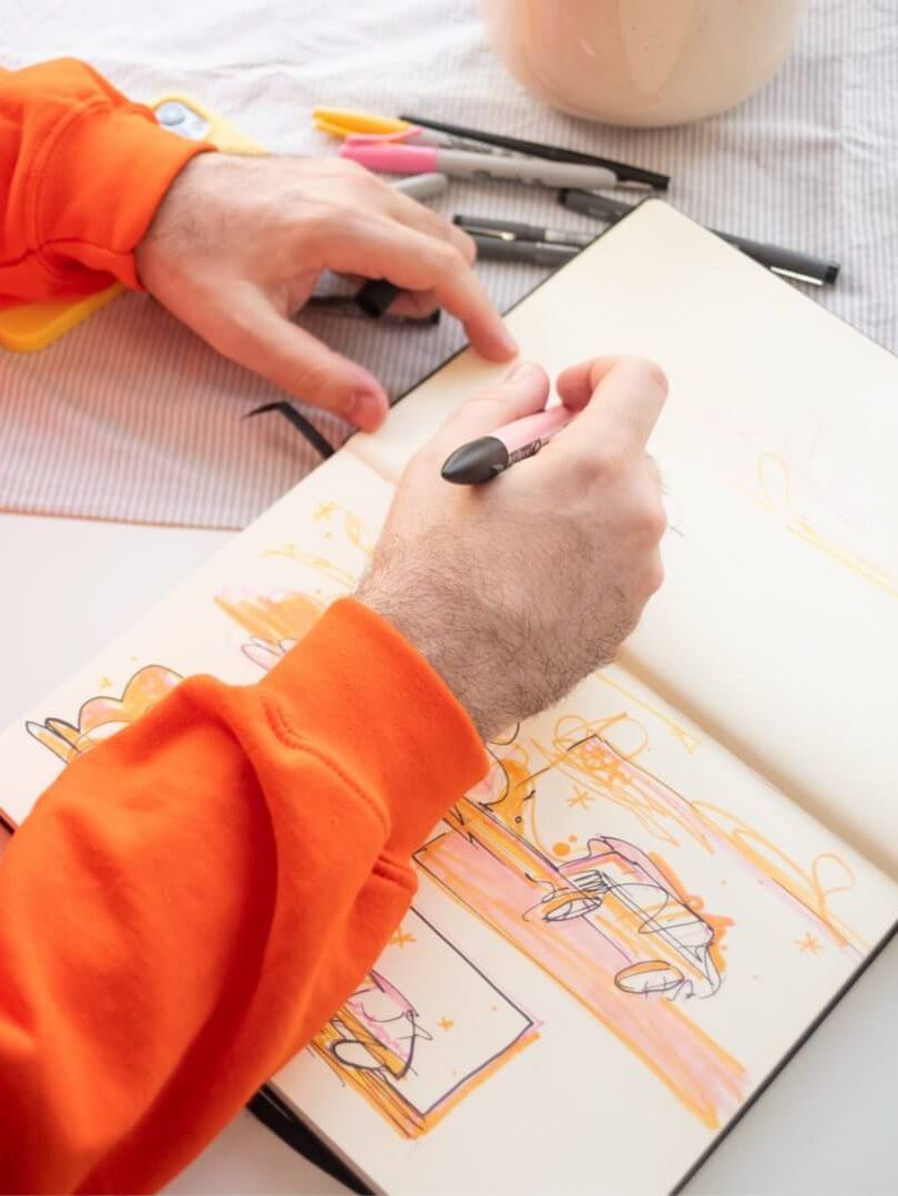 Person zeichnet in einem Notizbuch Skizzen