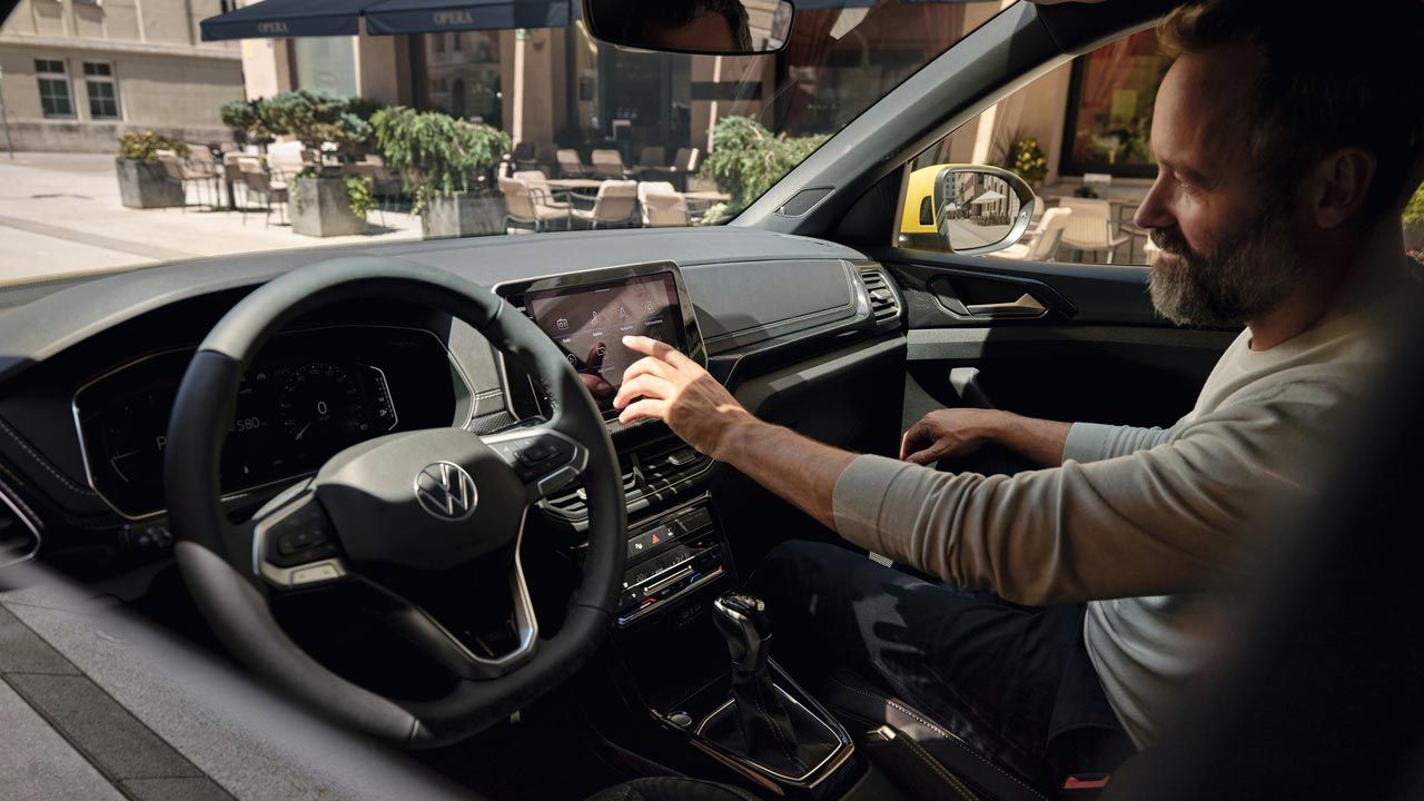 Ein Mann bedient vom Beifahrersitz aus den Bildschirm des VW T-Cross