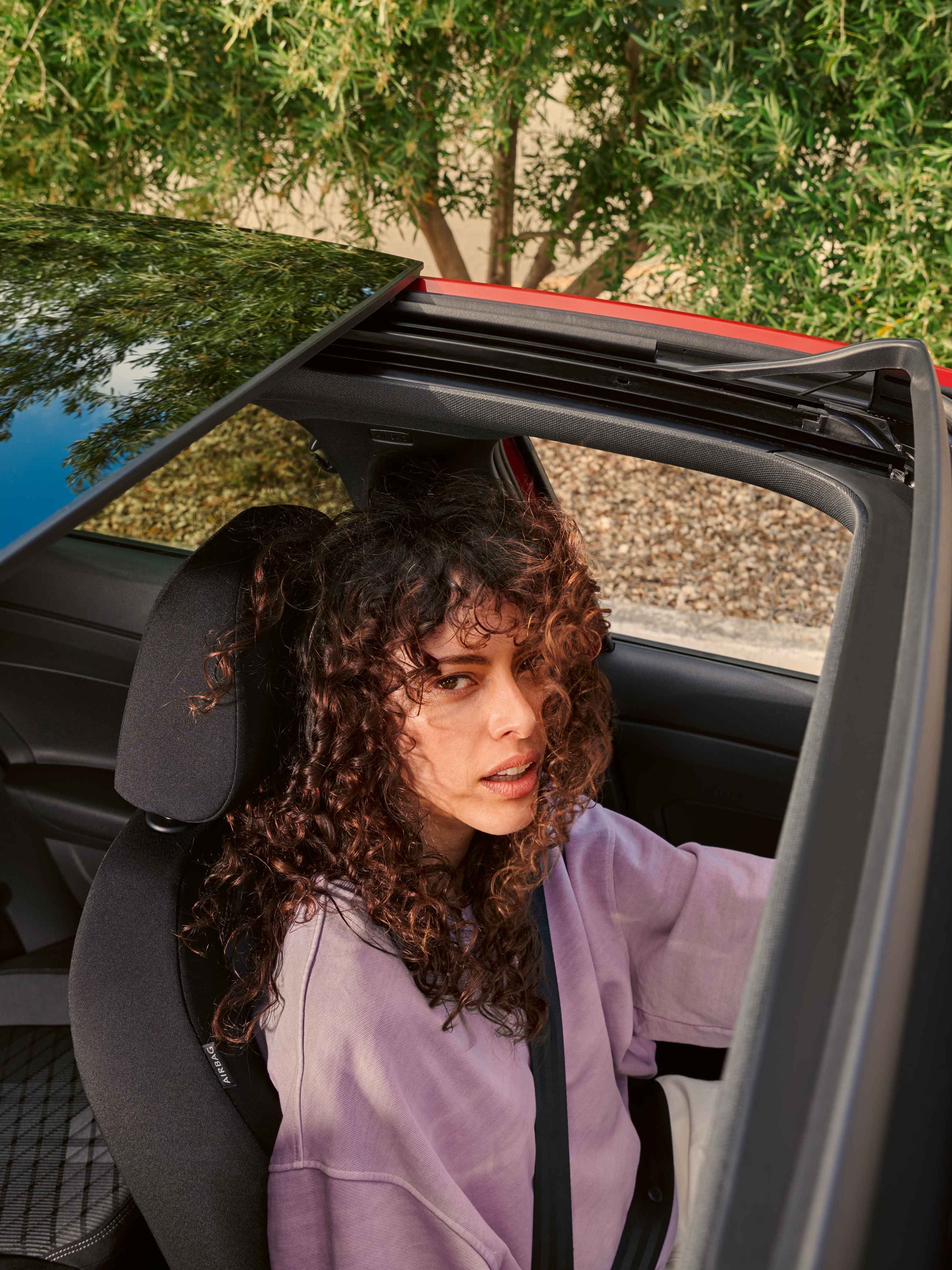 Blick von oben durch das Panoramadach des VW Taigo in dem eine Frau am Fahrersitz sitzt