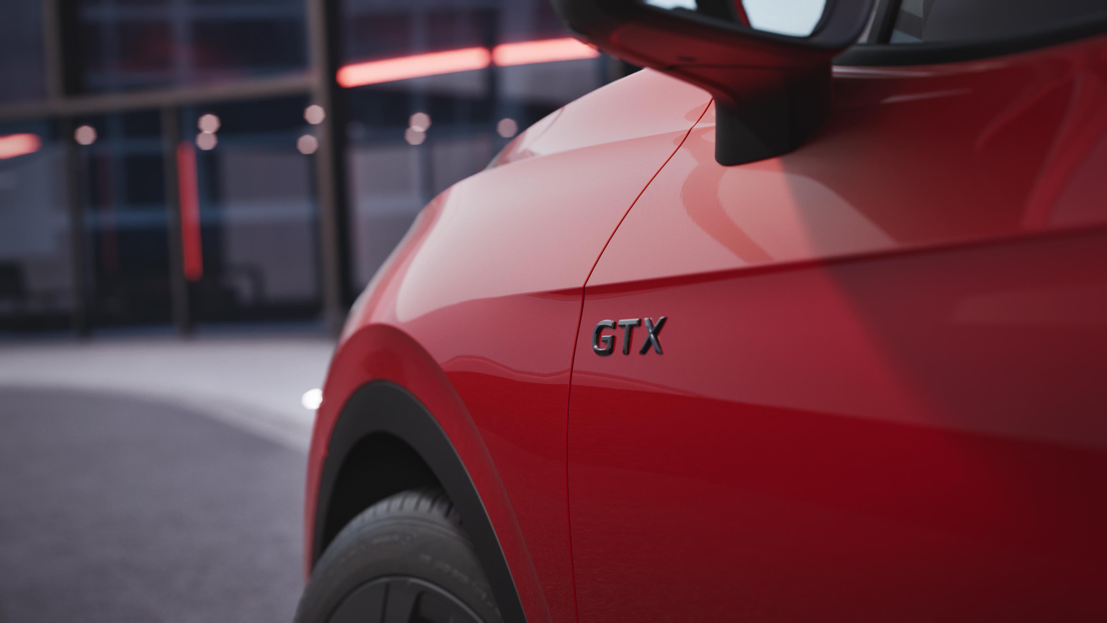 Detailansicht des schwarzen GTX Schriftzugs unterhalb des linken Außenspiegels eines roten VW ID.4 GTX