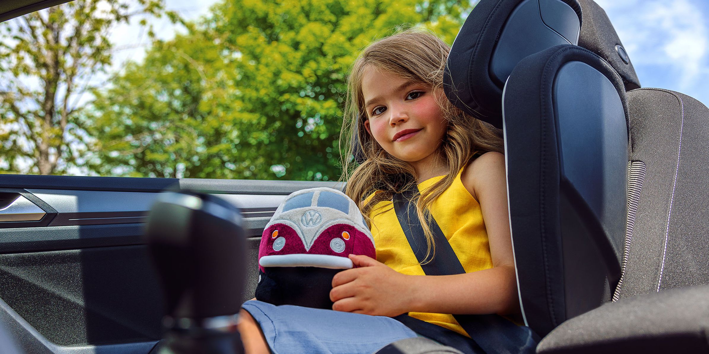 Ein Mädchen im Kindersitz mit einem VW Plüsch Bulli am Schoß