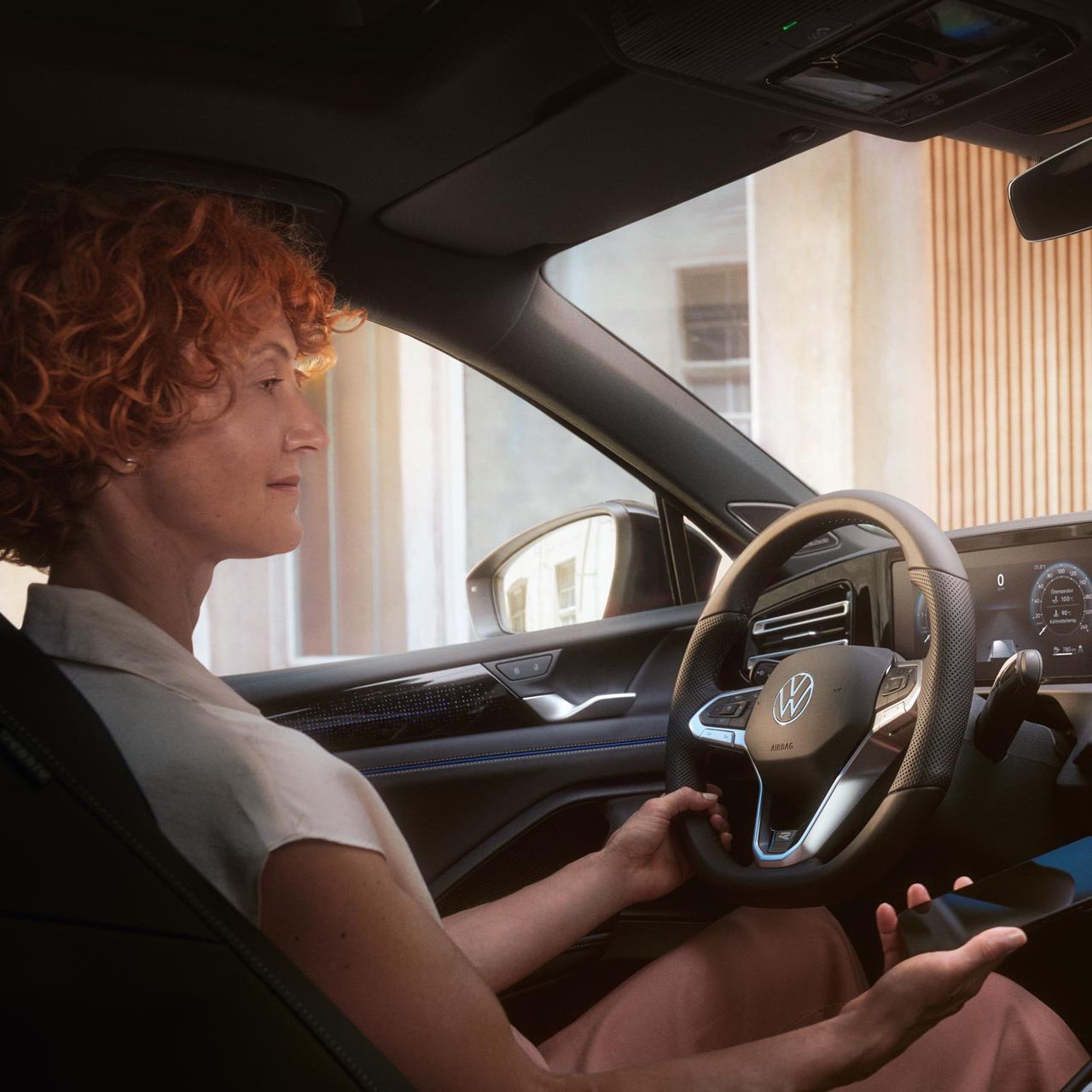 Frau blickt auf das Infotainmentsystem im VW Tiguan und hält Smartphone in ihrer Hand