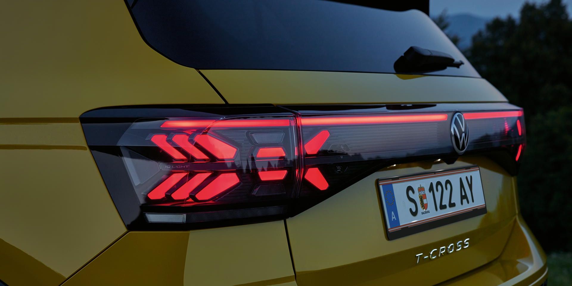 IQ. LIGHT Rückbeleuchtung eines gelben VW T-Cross in Großaufnahme in der Dämmerung.
