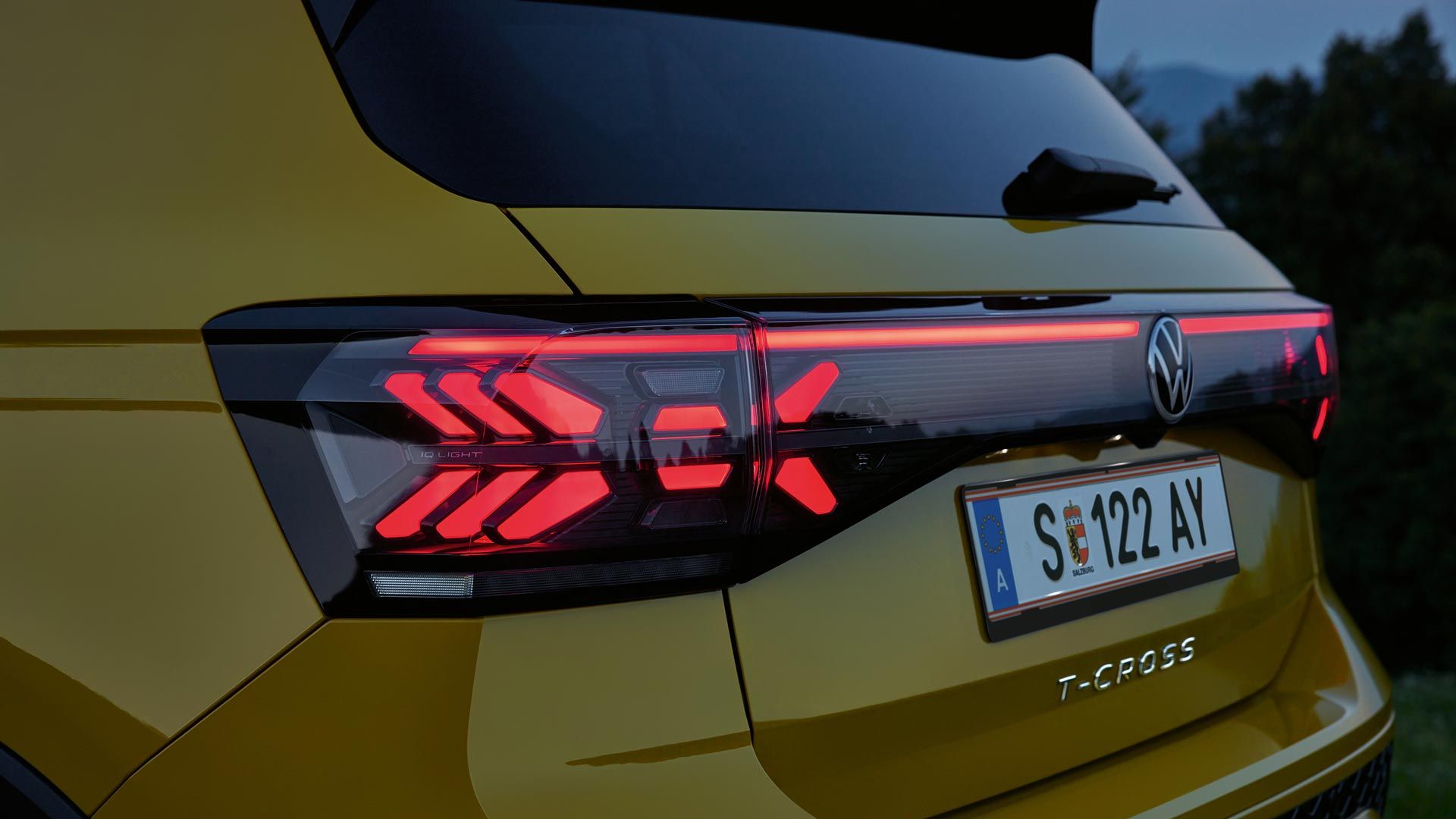 IQ. LIGHT Rückbeleuchtung eines gelben VW T-Cross in Großaufnahme in der Dämmerung.