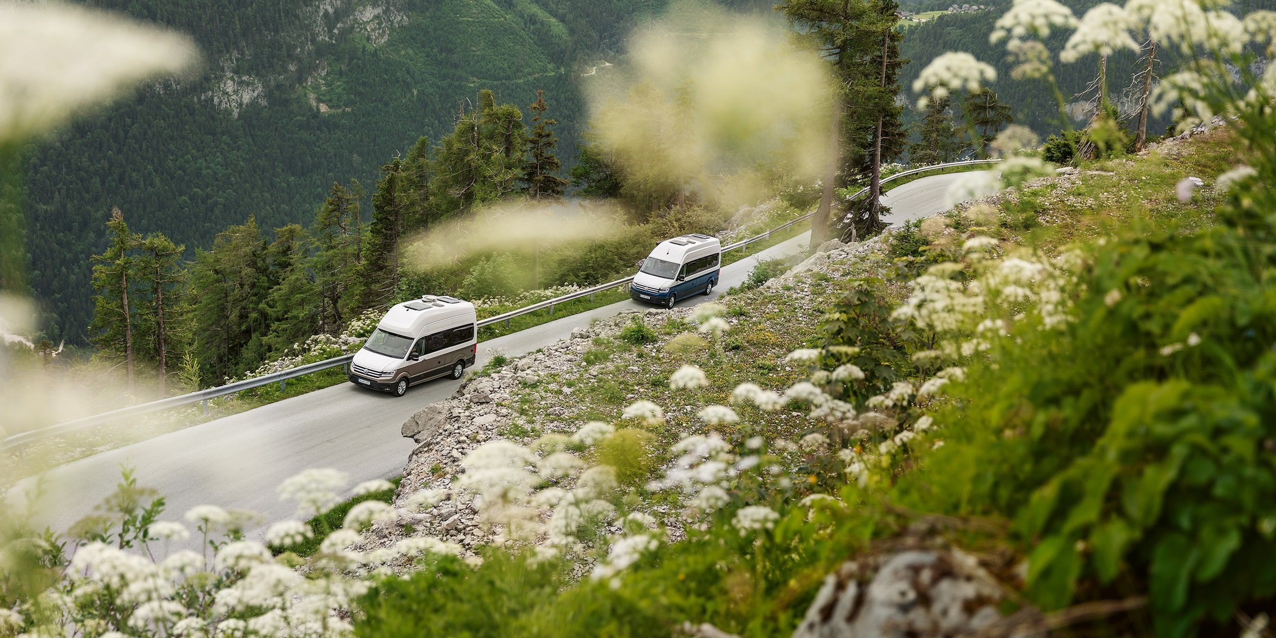 zwei VW Grand California in Fahrt auf einer Bergstraße