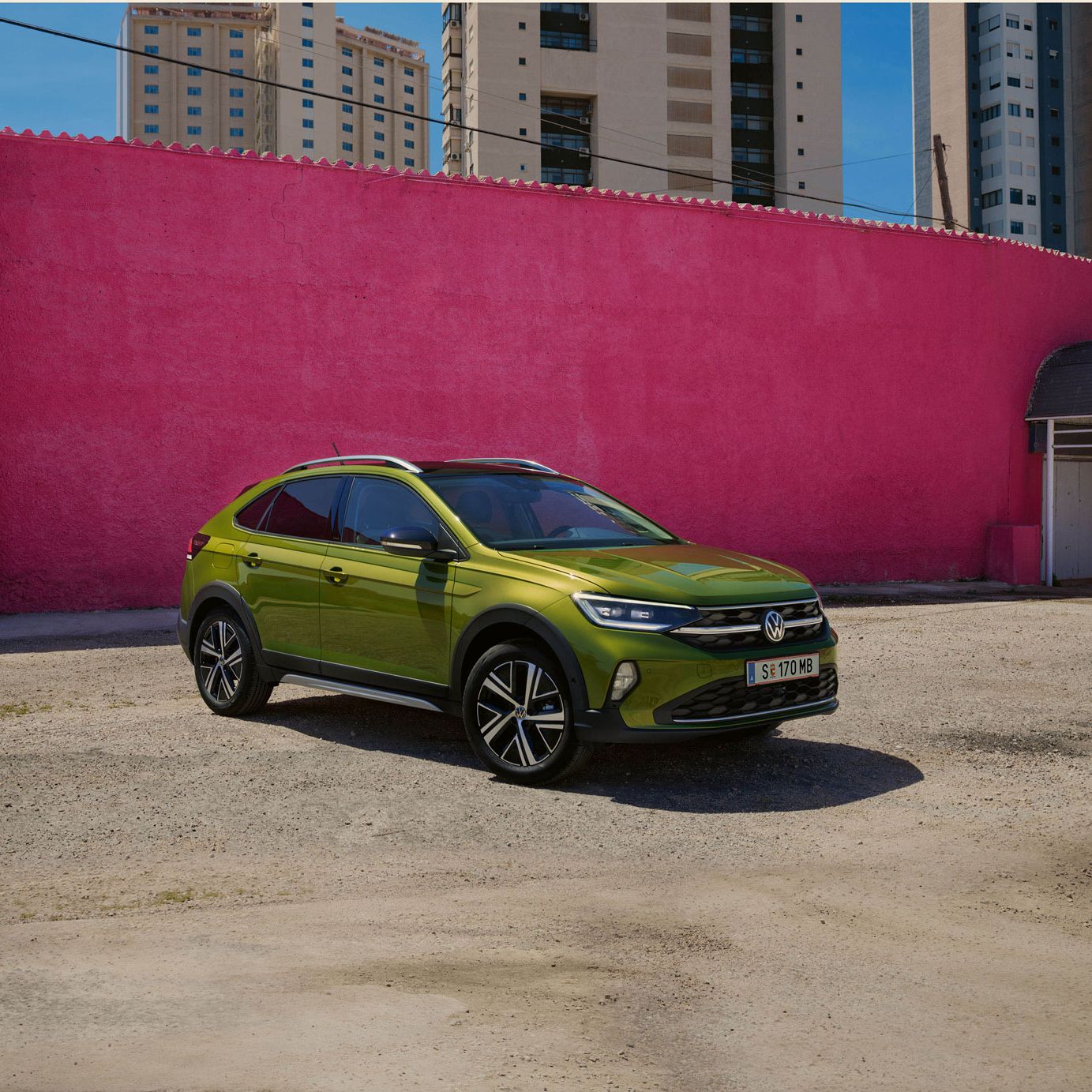 Grüner VW Taigo Style geparkt vor einer pinken Wand