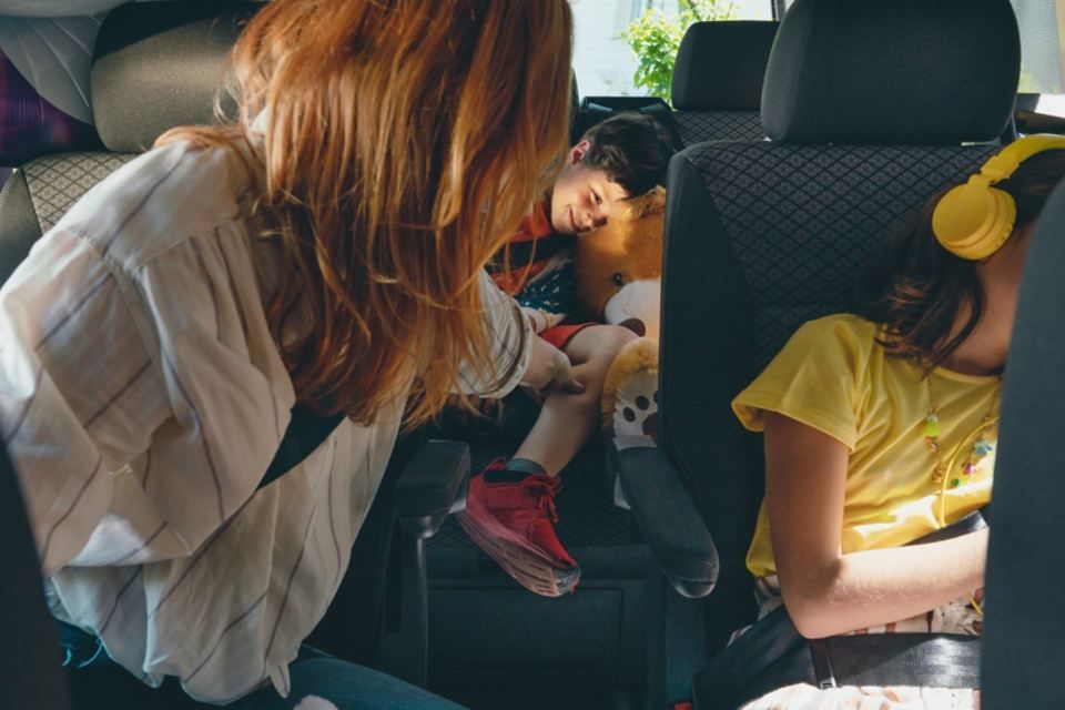 Zwei Kinder und eine Frau sitzen auf Rückbänken eines VW Multivans 6.1.