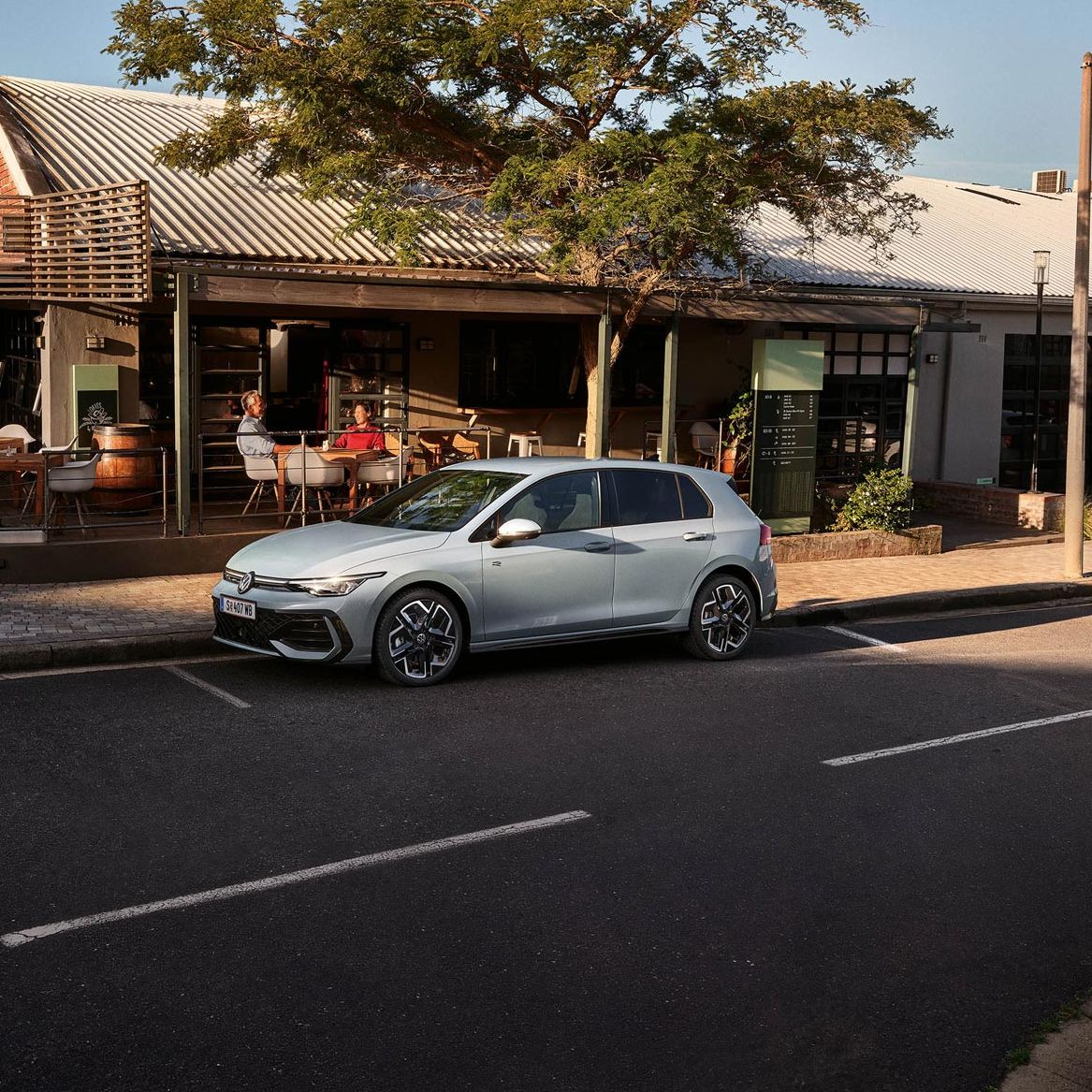 Der neue Golf GTE parkt an einem Straßenrand neben einem Café.