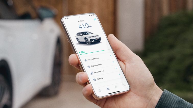 Mann hält Smartphone in der Hand, auf dem Bildschirm sieht man die VW Connect für ID. App, im Hintergrund steht ein weißer ID.5