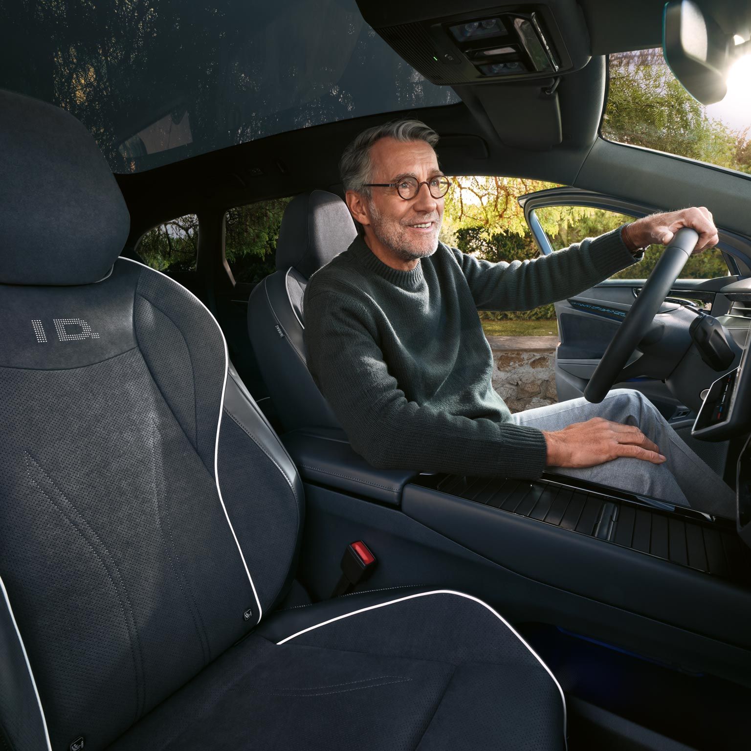 Mann sitzt am Fahrersitz des geparkten VW ID.7 Tourer, die Fahrertür ist geöffnet