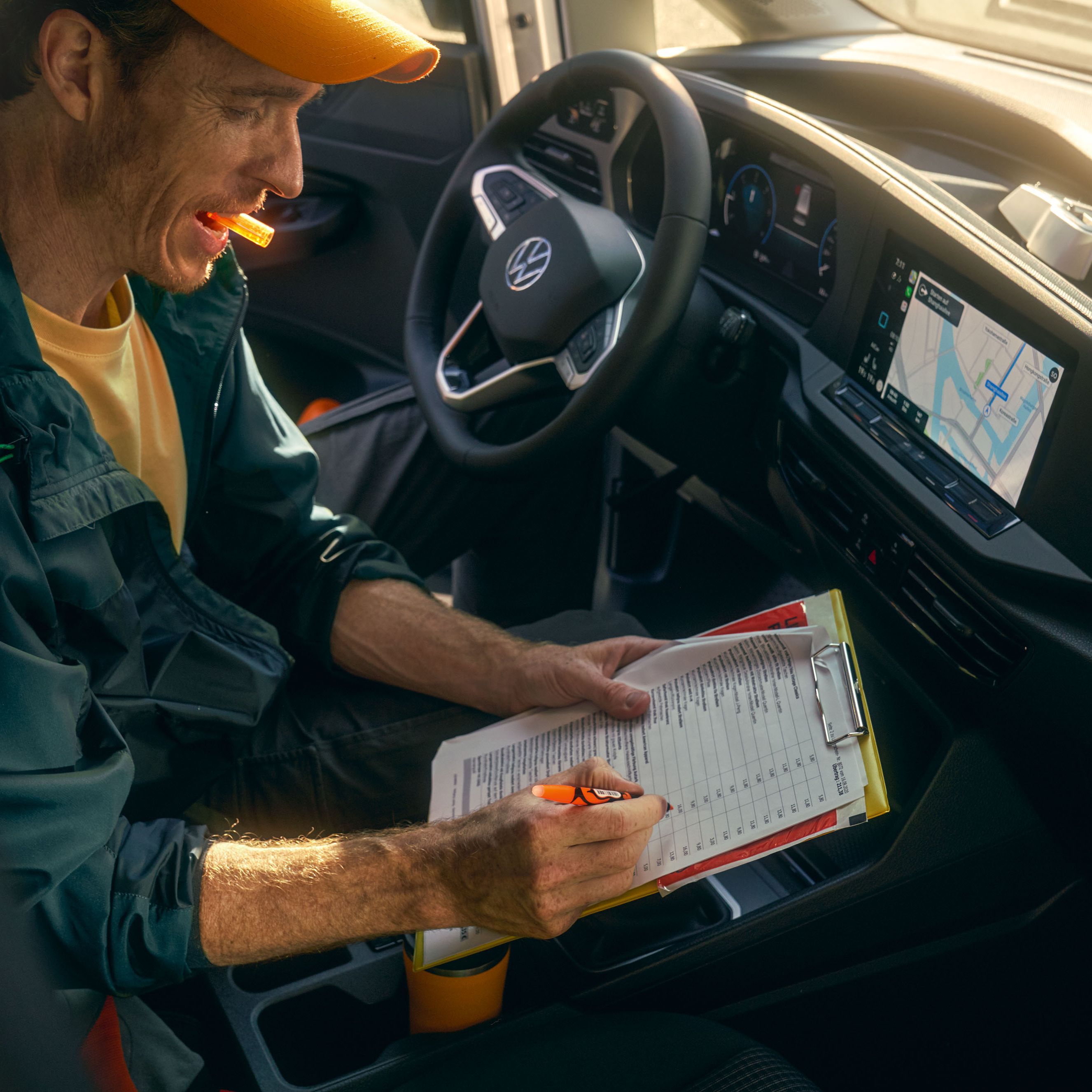 Ein Mann sitzt in einem VW Caddy Cargo und schreibt auf einem Klemmbrett.
