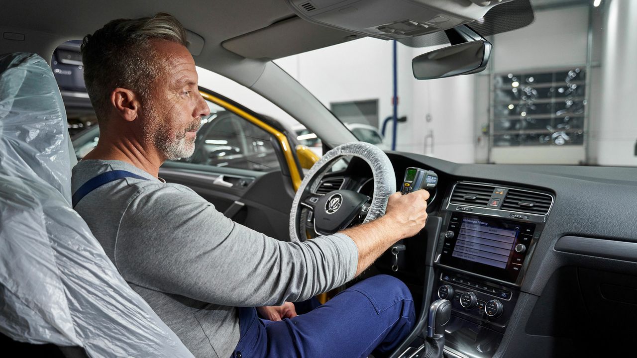 Ein Volkswagen Service Techniker sitzt in einem Volkswagen und testet die Klimaanlage