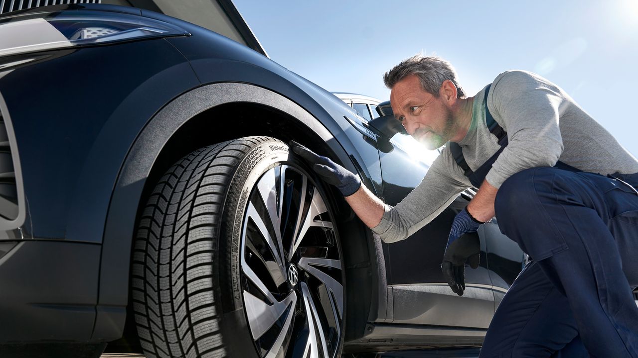 Mechaniker beim Prüfen der Reifen eines VW Fahrzeuges