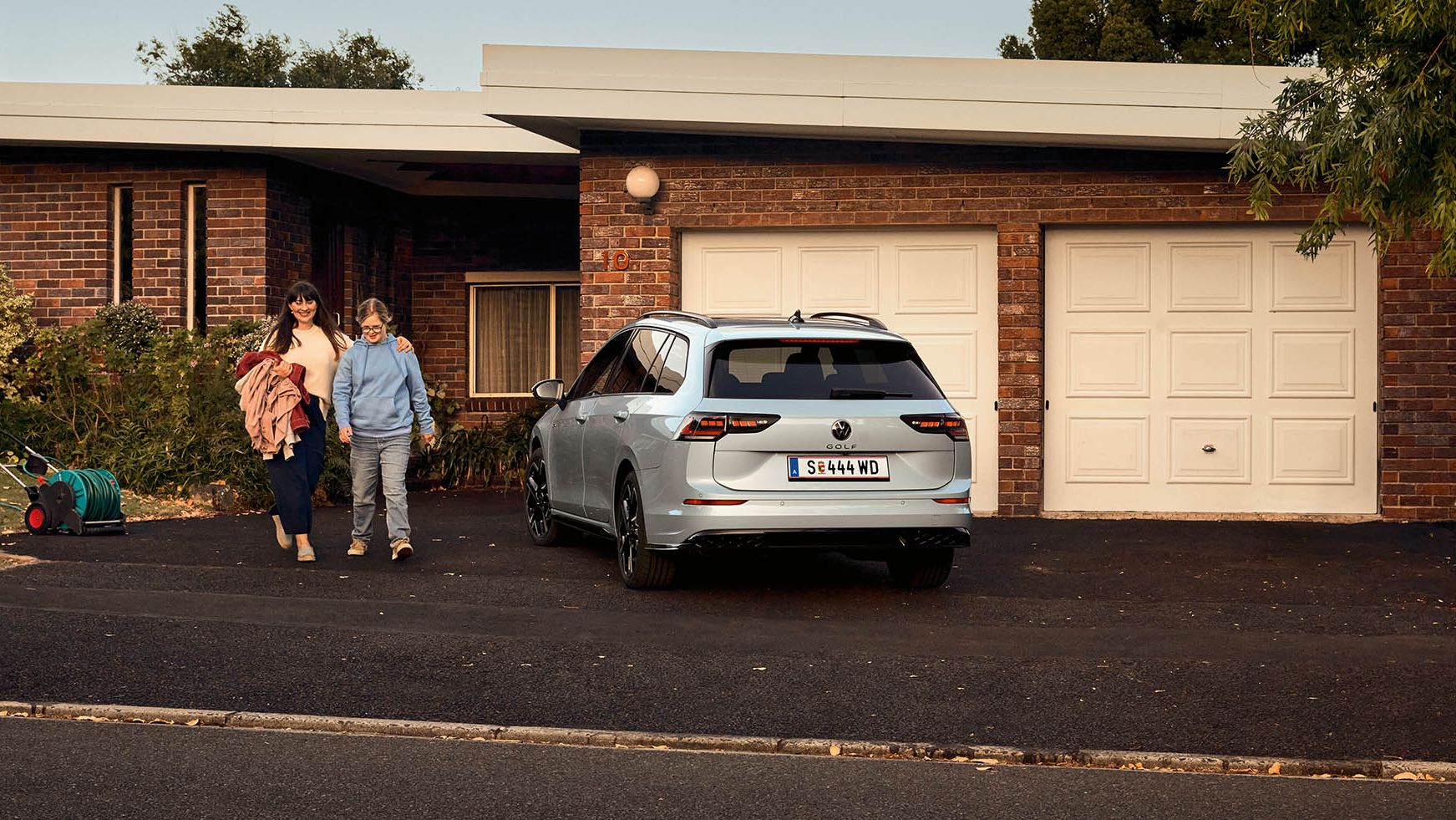 Heckansicht eines VW Golf Variant in der Farbe Ice Blue Metallic geparkt vor Einfamilienhaus