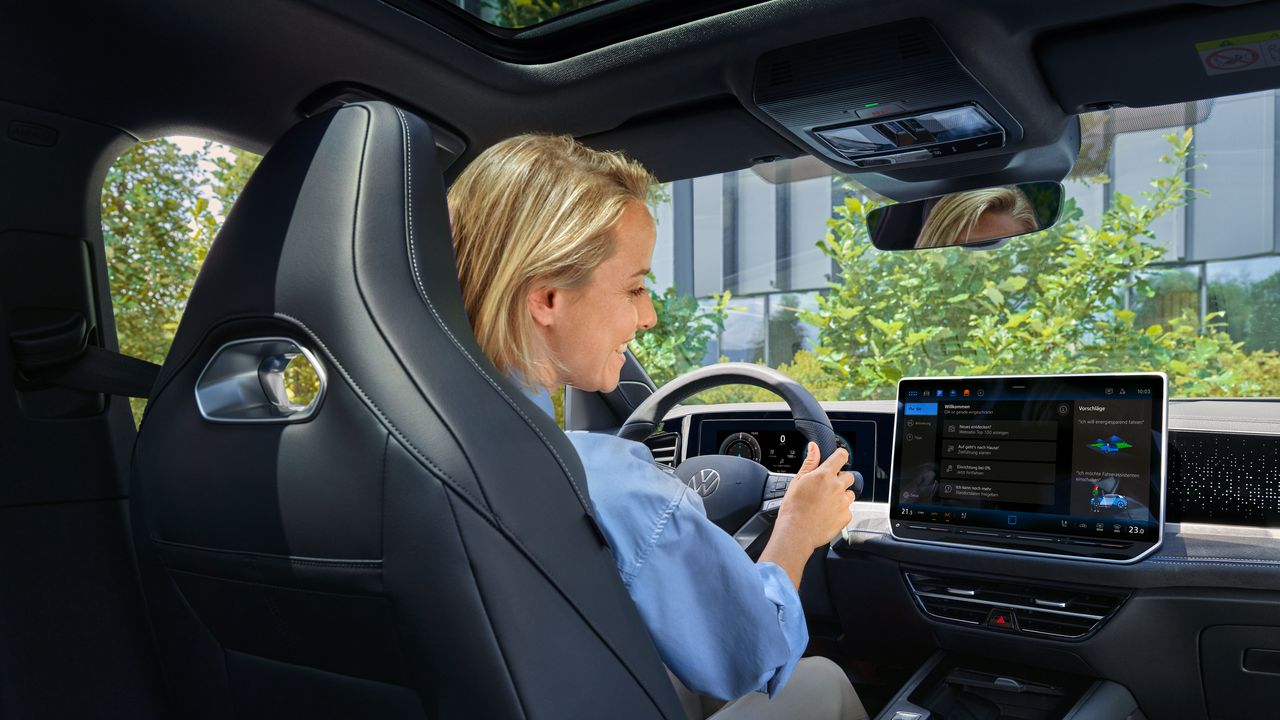 Eine Frau sitzt im VW Passat und blickt auf das Infotainmentsystem