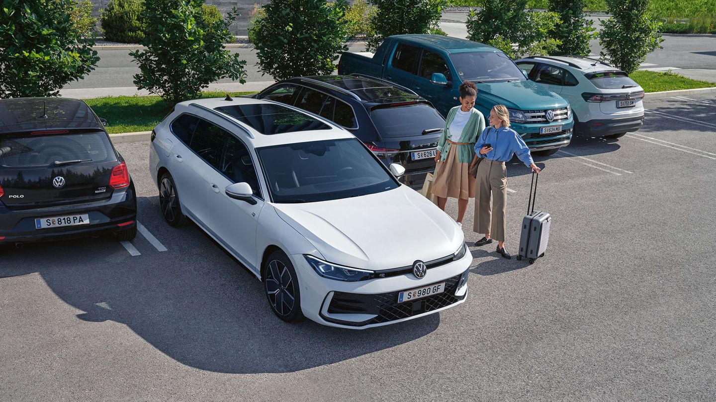 Zwei Frauen stehen auf einem Parkplatz neben einem weißen VW Passat B9