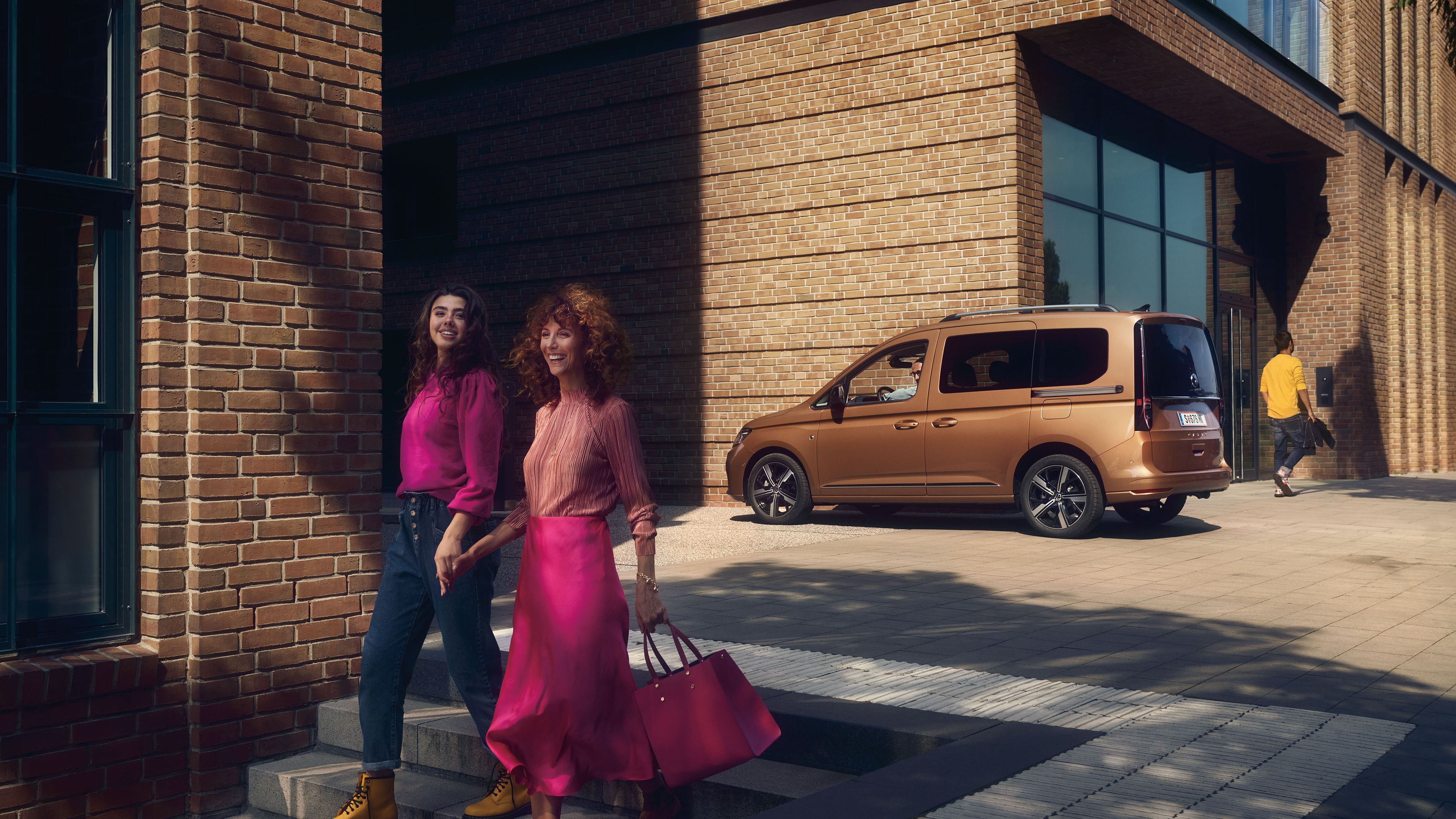 Die Mutter geht mit ihrer Tochter die Stiege hinunter, dahinter ist ein VW Caddy zu sehen.