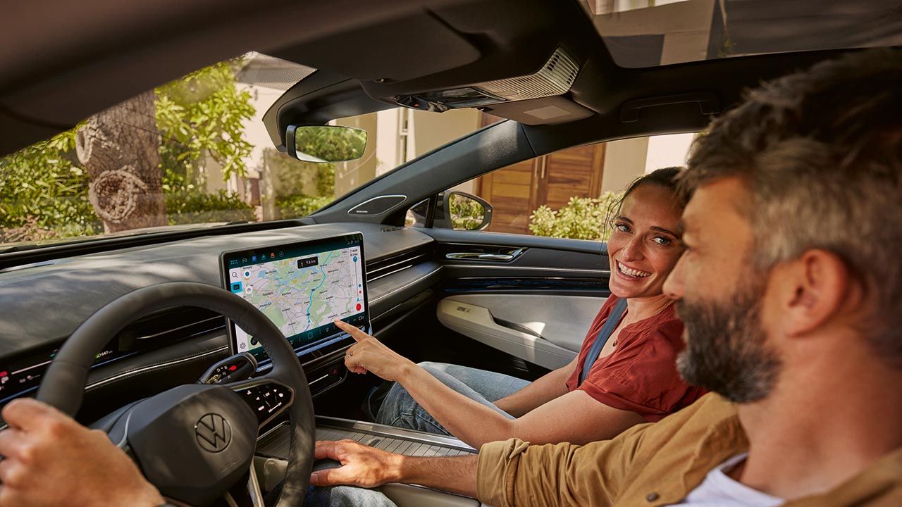 Ein Mann und eine Frau sitzen im VW, sie zeigt auf den Navi-Bildschirm