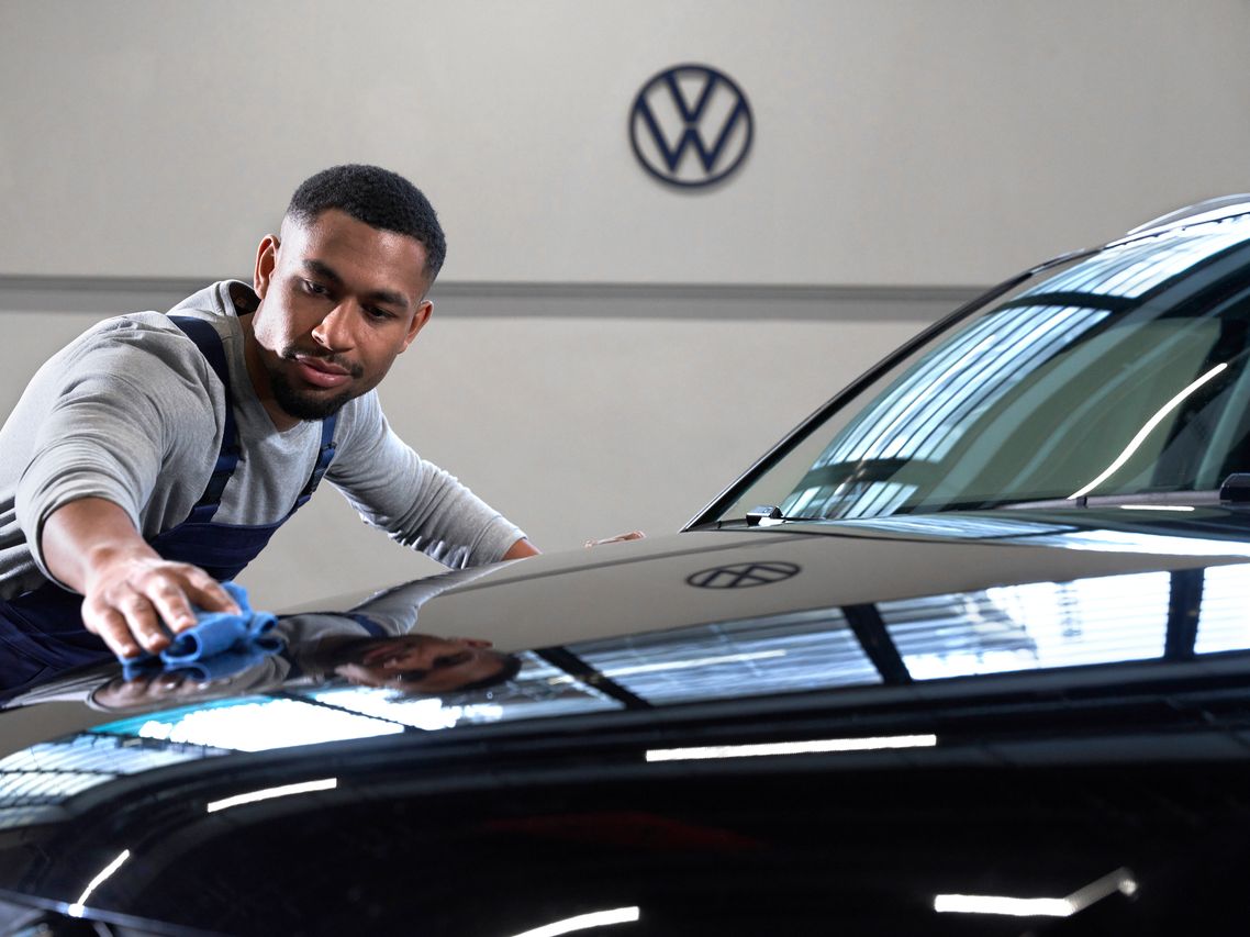 Service-Mitarbeiter wischt Motorhaube eines Volkswagen Fahrzeug