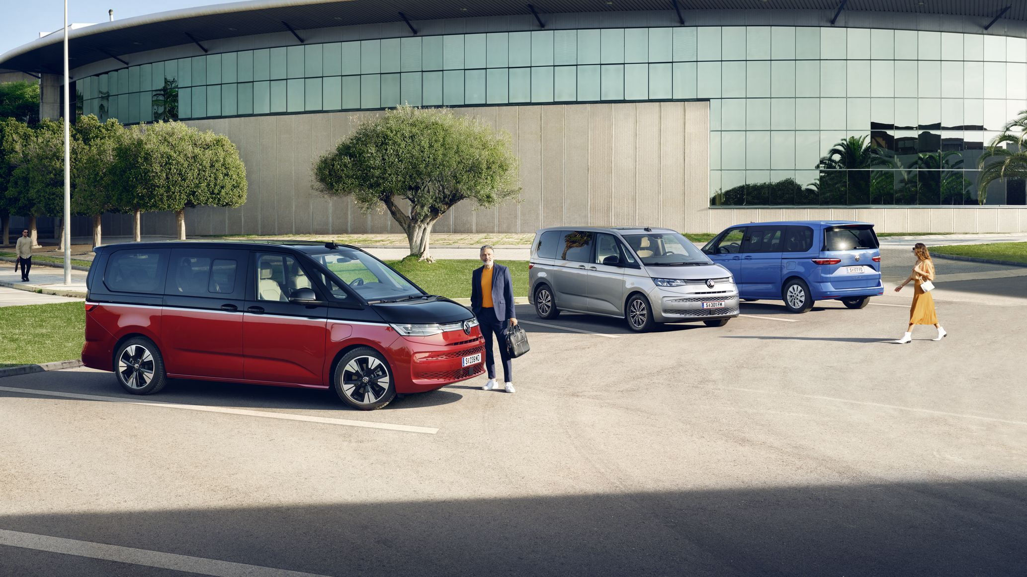 Drei unterschiedliche Varianten des VW Multivan T7 2021 stehen auf einem Parkplatz.